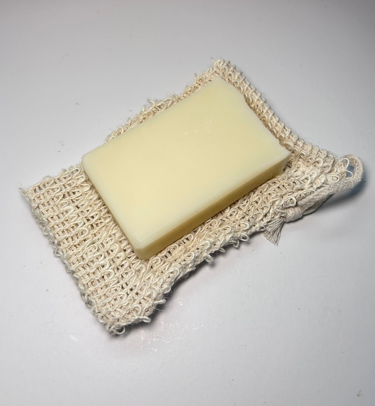 Bar of soap on a natural fiber soap dish against a plain background