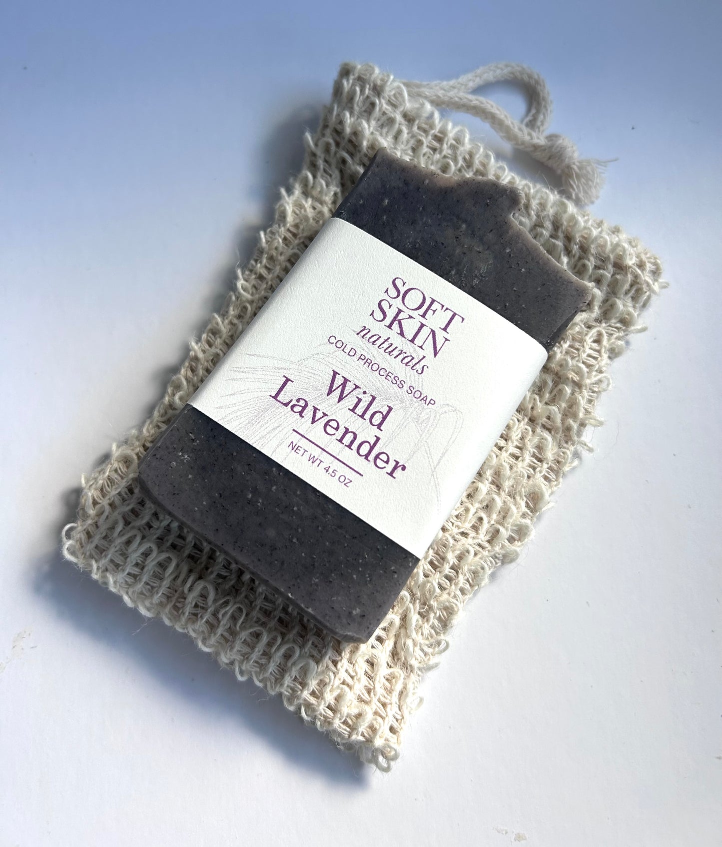 Bar of Wild Lavender soap on a natural fiber soap dish with Soft Skin Naturals branding.