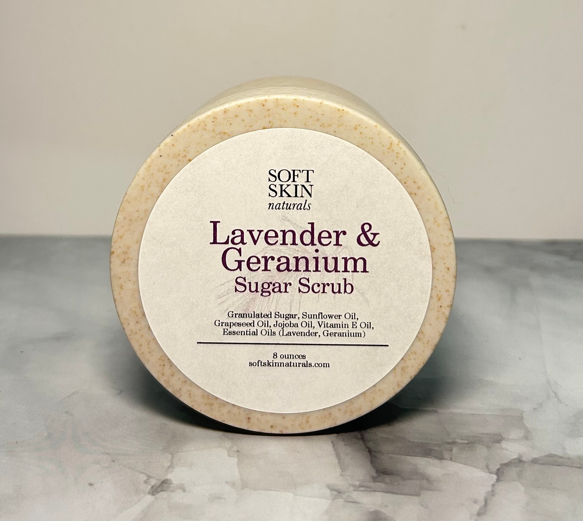 Lavender Geranium sugar scrub jar on a marbled surface.