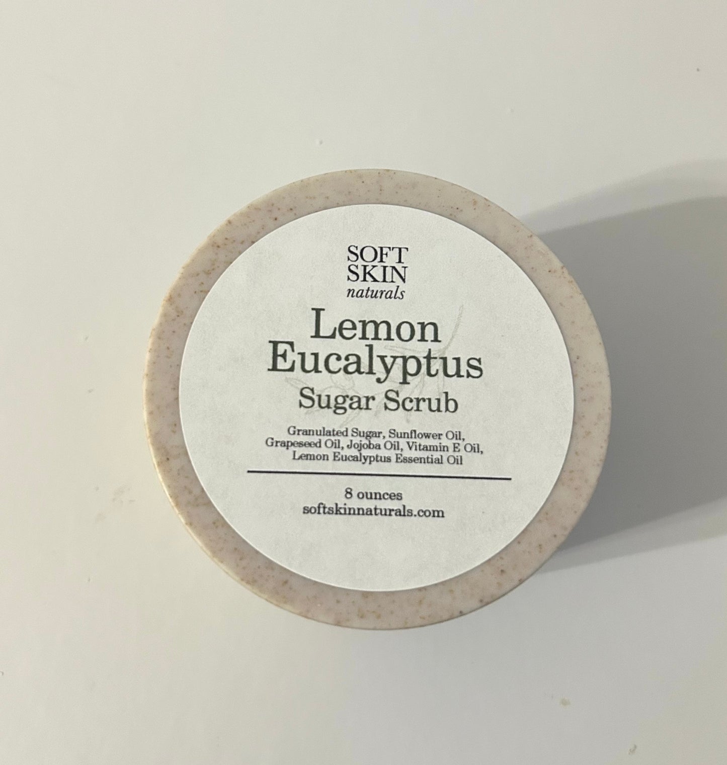 Round container of Lemon Eucalyptus Sugar Scrub by Soft Skin Naturals on a light background