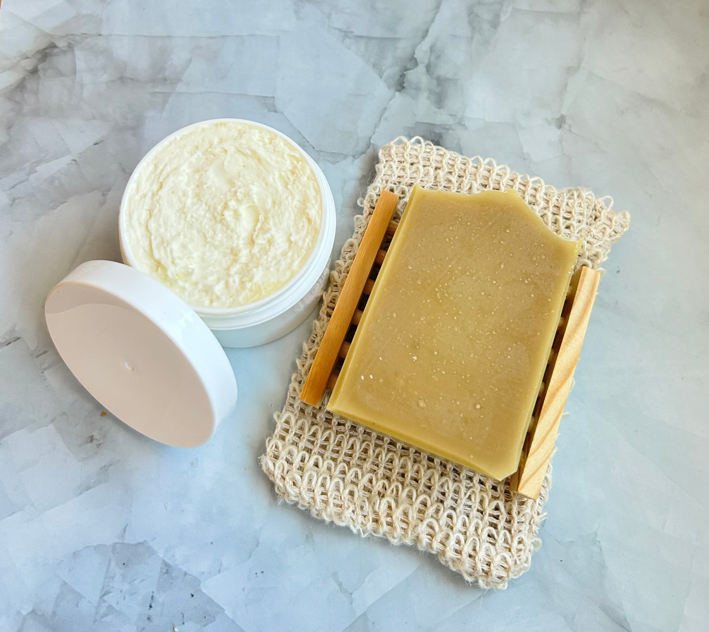 Bar of soap and a container of body butter on a textured surface
