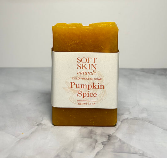 Bar of pumpkin spice soap in a white container on a marble surface