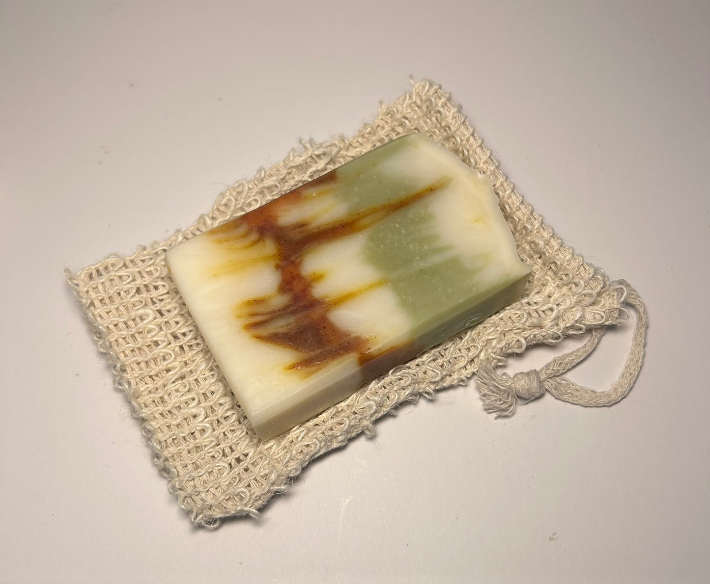 Bar of soap with brown and green stripes on a textured white surface