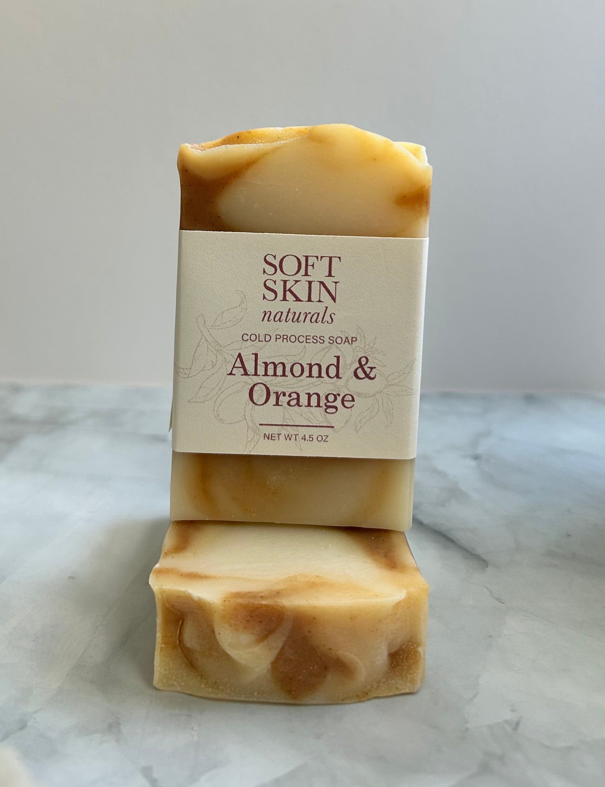 Two bars of soap with a 'Soft Skin Naturals' label on a marble surface.
