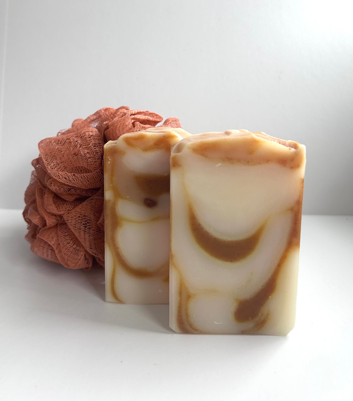 Two marbled soap bars with a brown scrubber on a white background