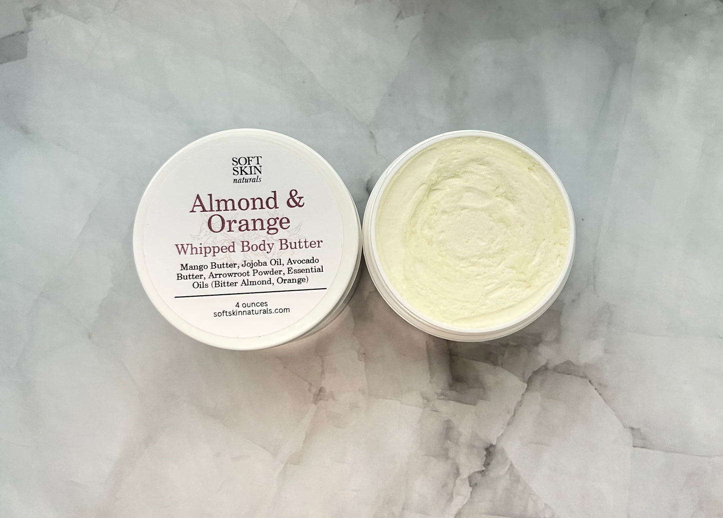 Almond & Orange whipped body butter with packaging on a marble surface
