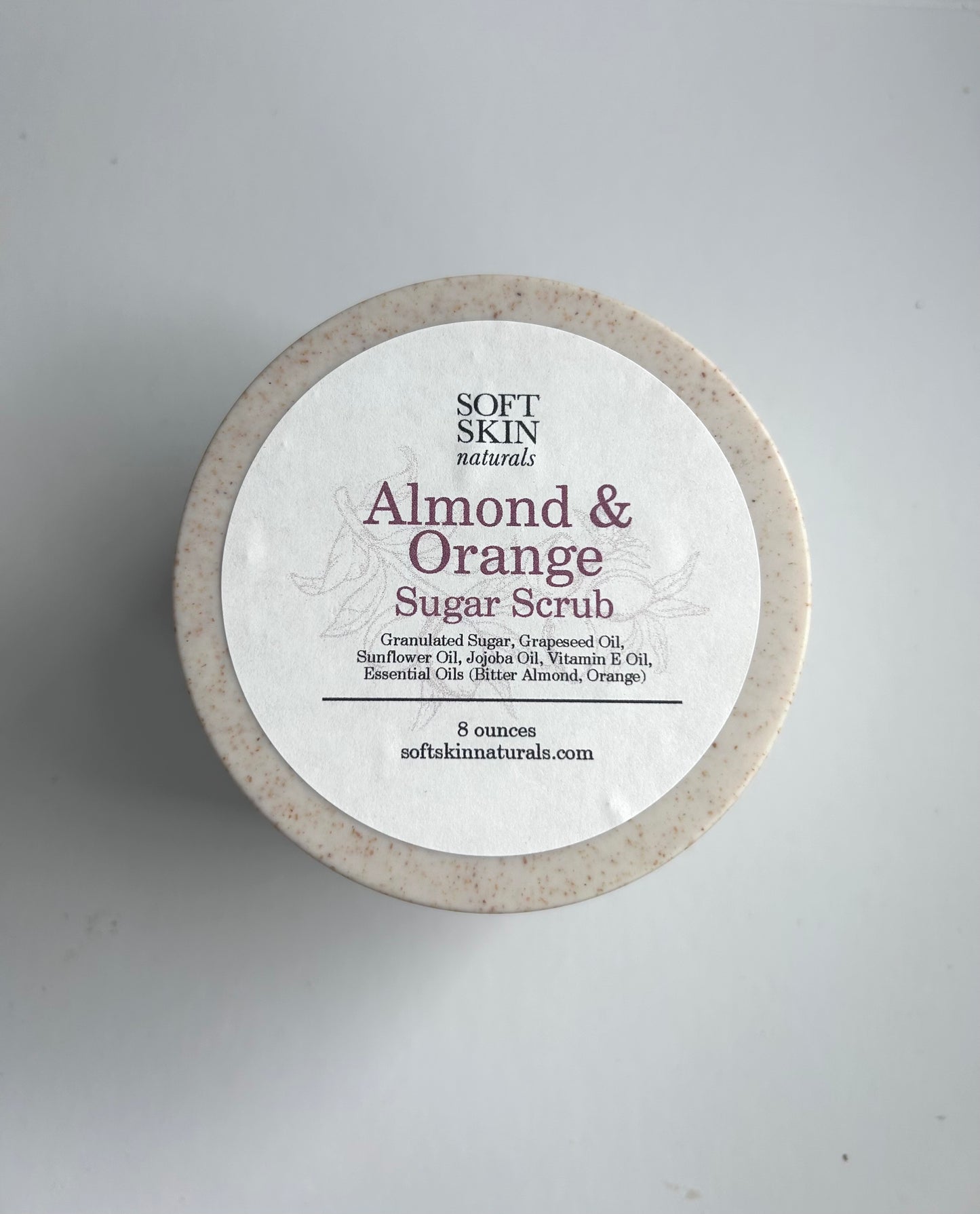 Almond & Orange Sugar Scrub container with label on a gray background