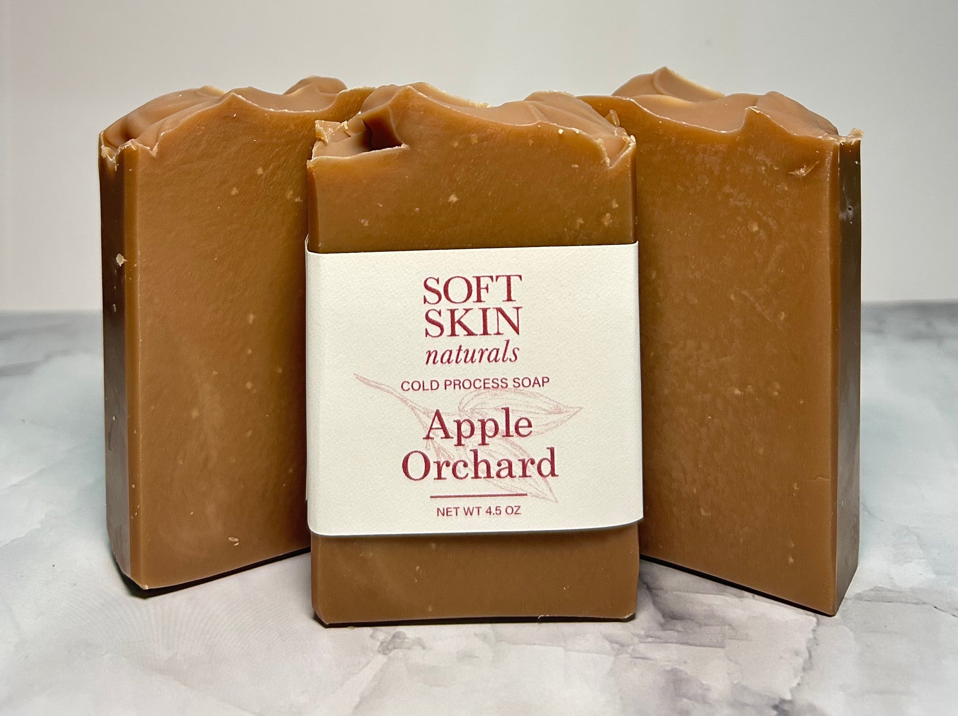 Three bars of Soft Skin Naturals Apple Orchard soap on a marble surface.