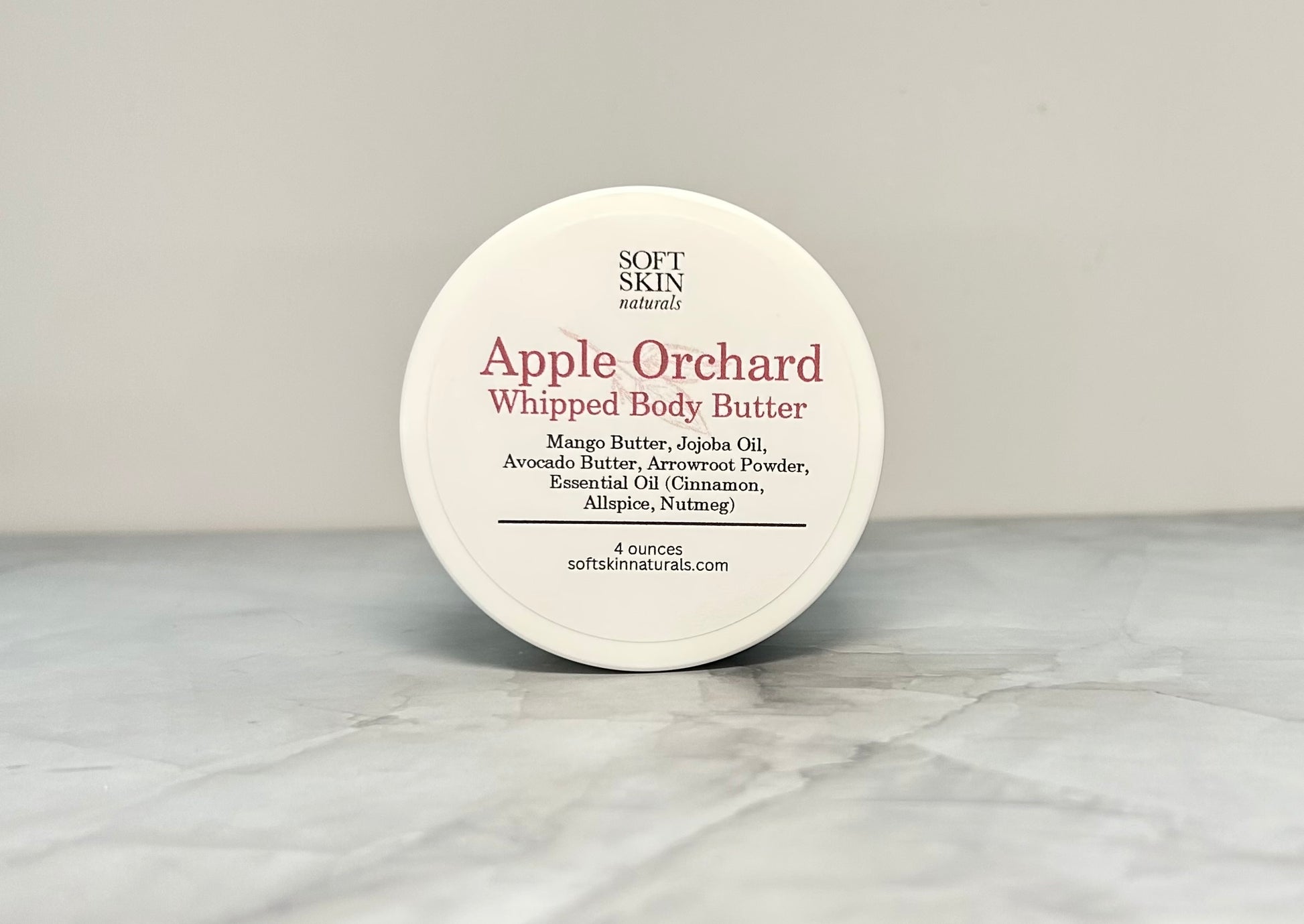 Jar of Apple Orchard whipped body butter sitting on a marbled table. 