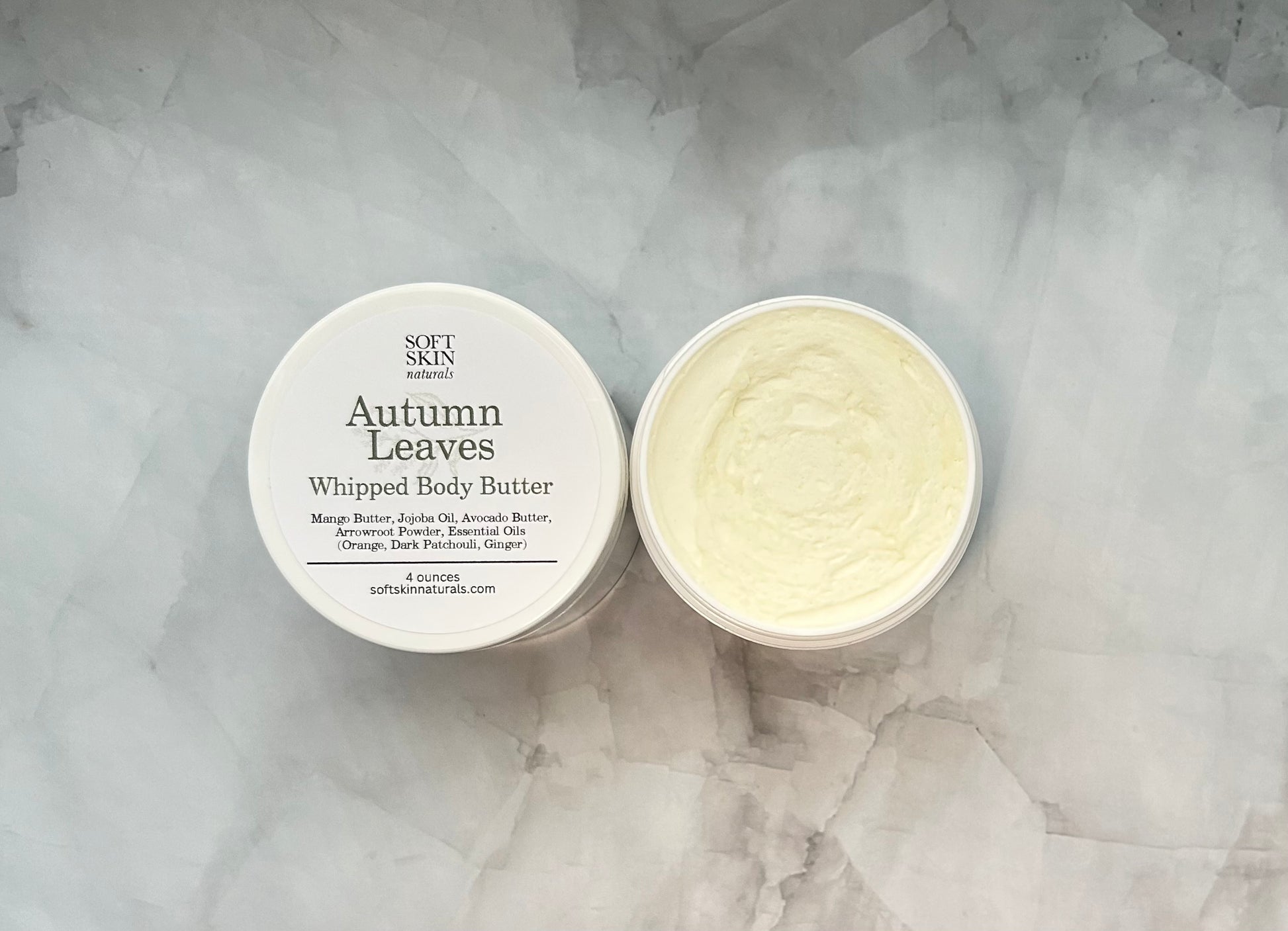 Two containers of 'Autumn Leaves' whipped body butter on a marble surface.