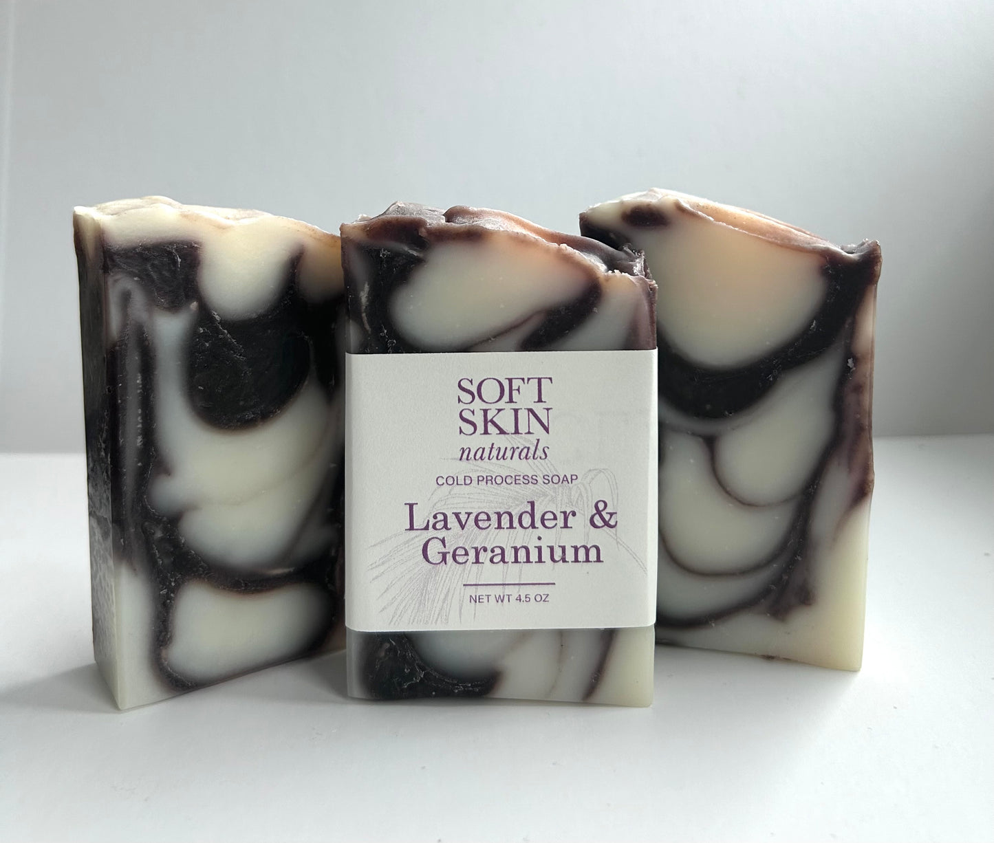 Three bars of soap with a central labeled bar on a white background