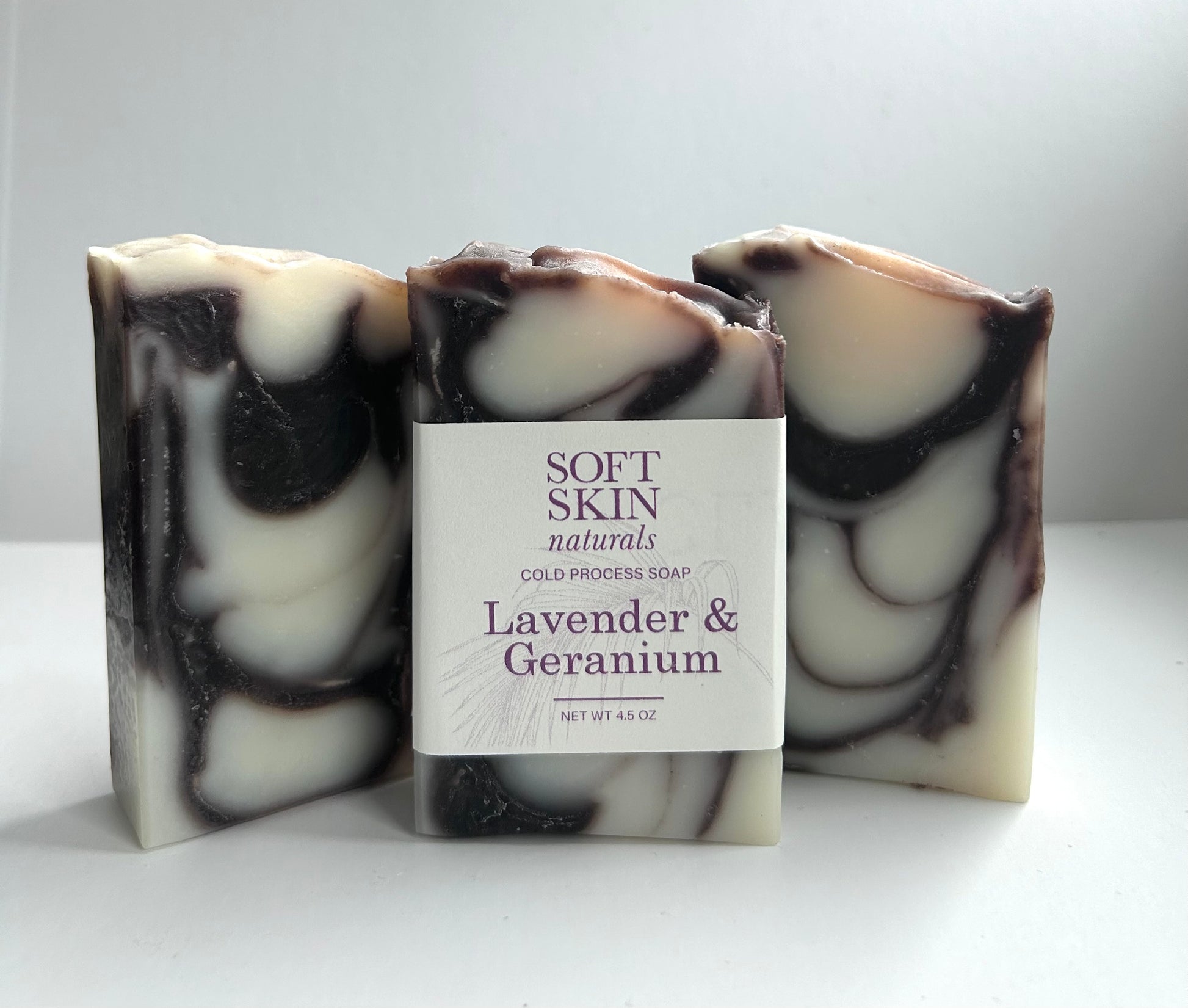 Three bars of soap with a central labeled bar on a white background