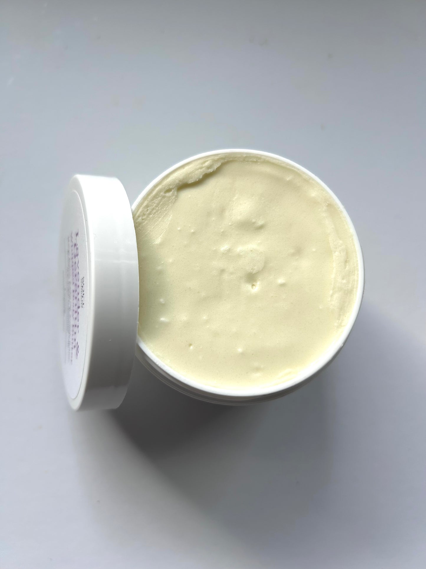 Open container of cream on a gray background