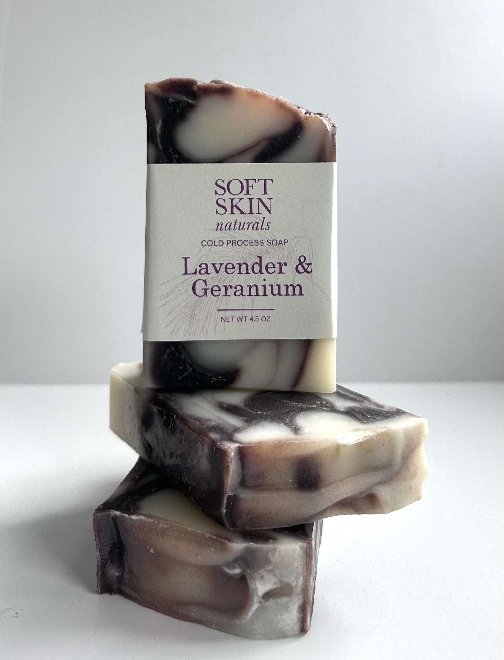 Stack of lavender and geranium soap bars with a visible label on a white background