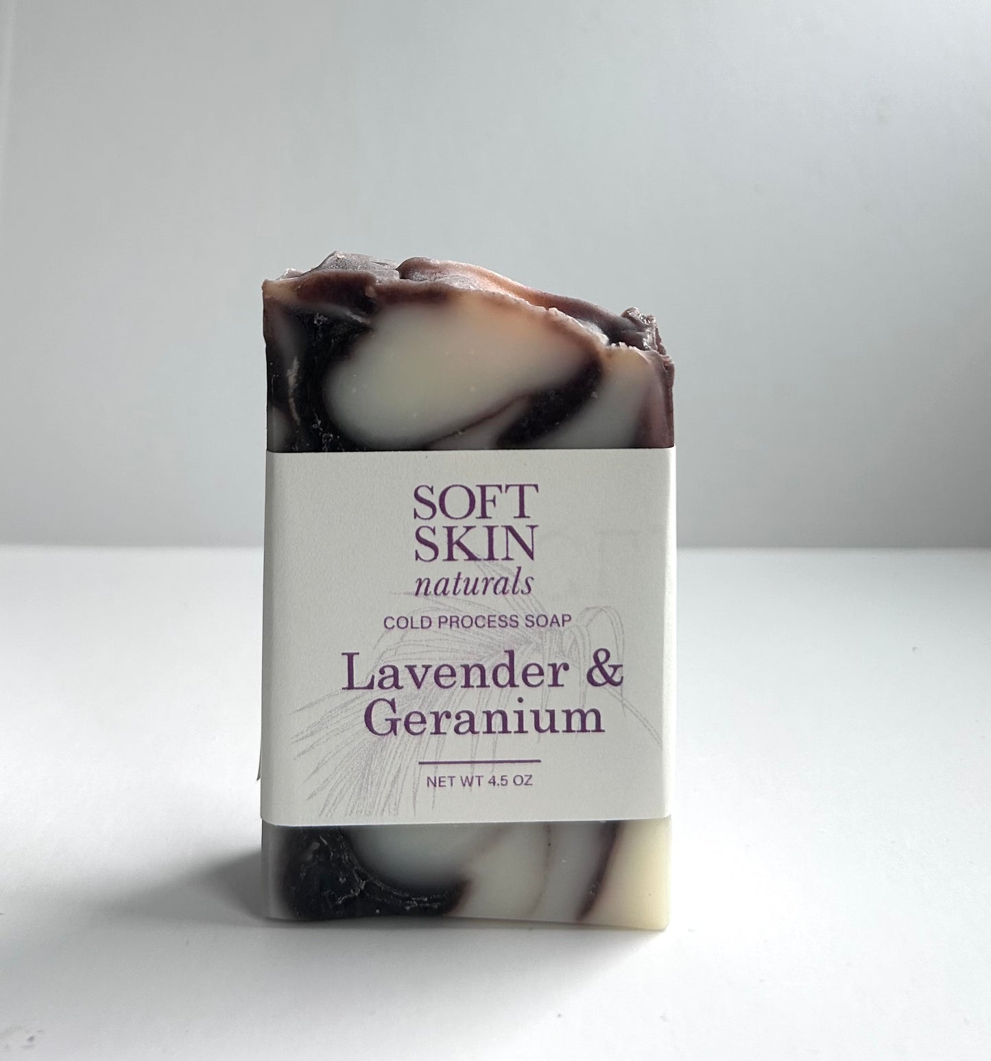 Marbled lavender and geranium soap bar with a label on a white background