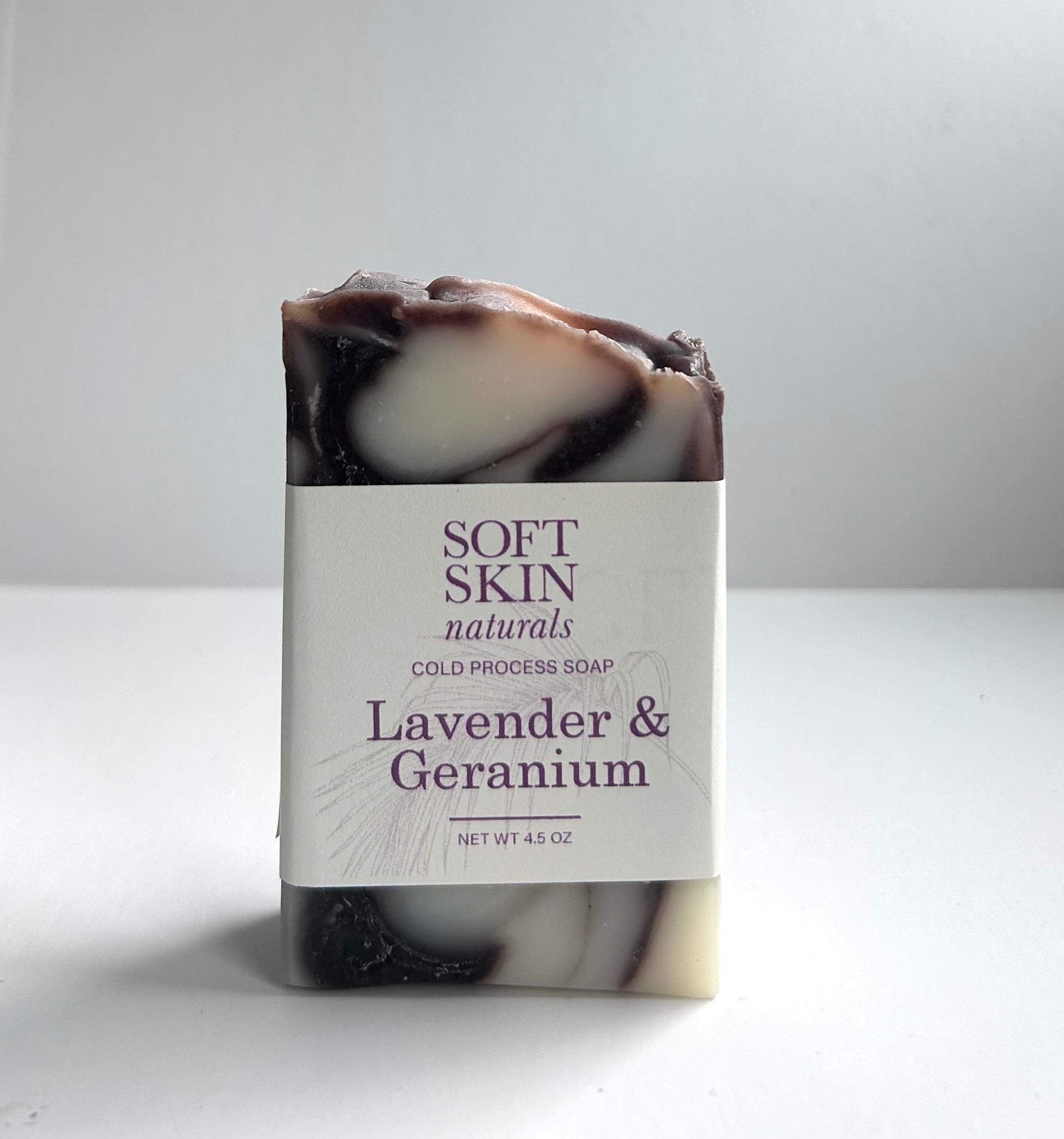 Marbled lavender and geranium soap bar with a label on a white background