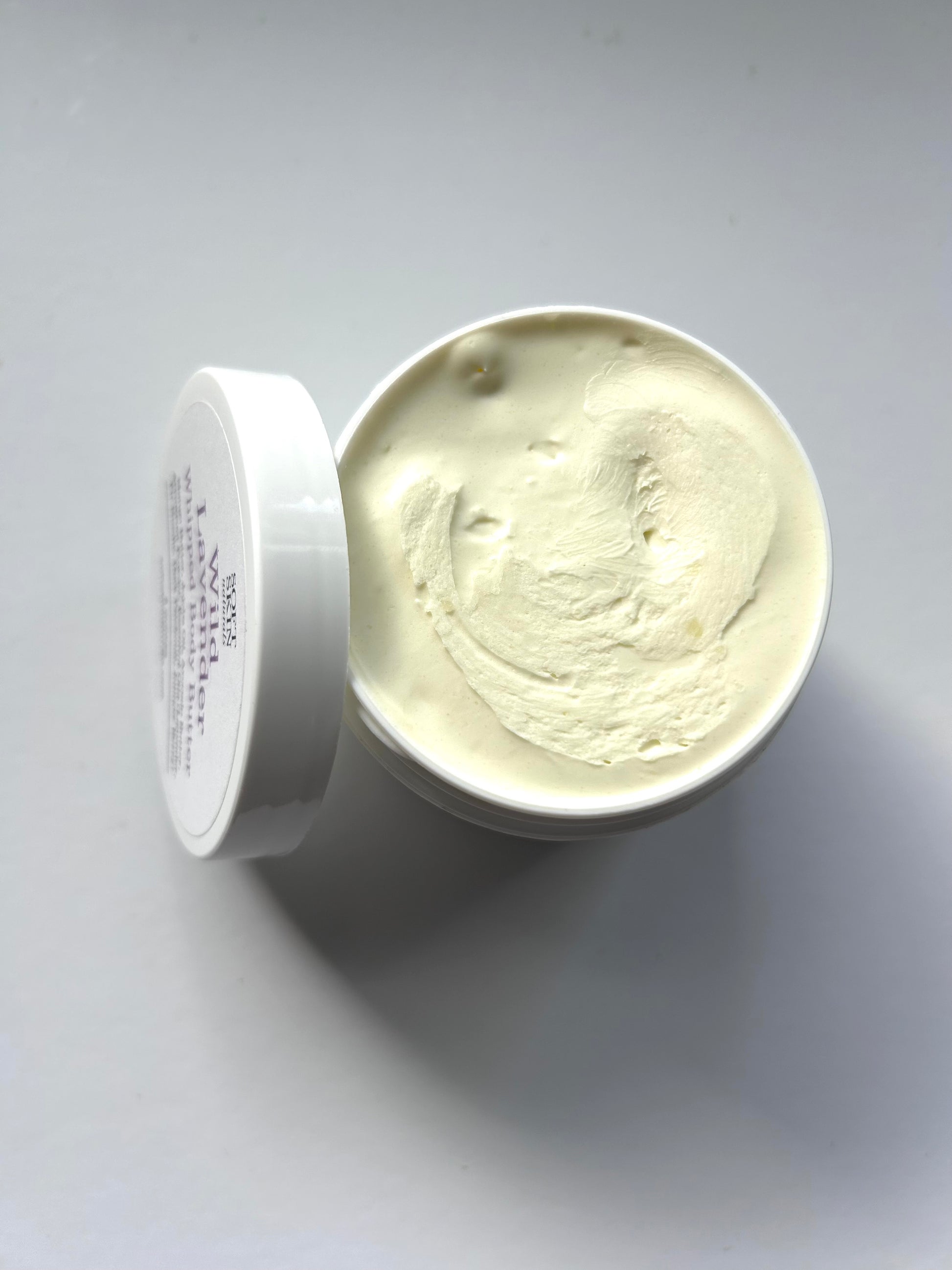 Open container of cream on a gray background