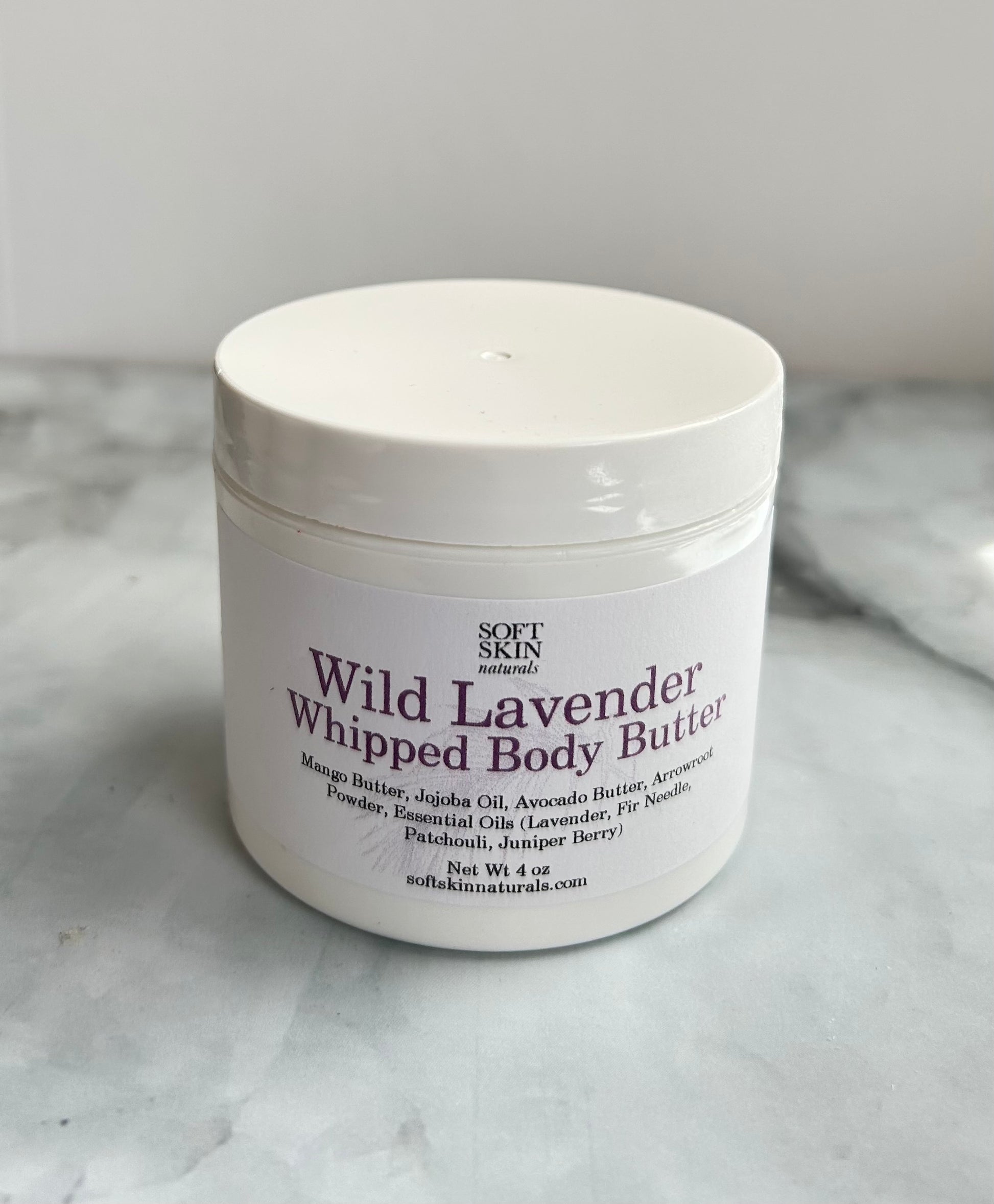 White jar of Wild Lavender Whipped Body Butter on a marble surface
