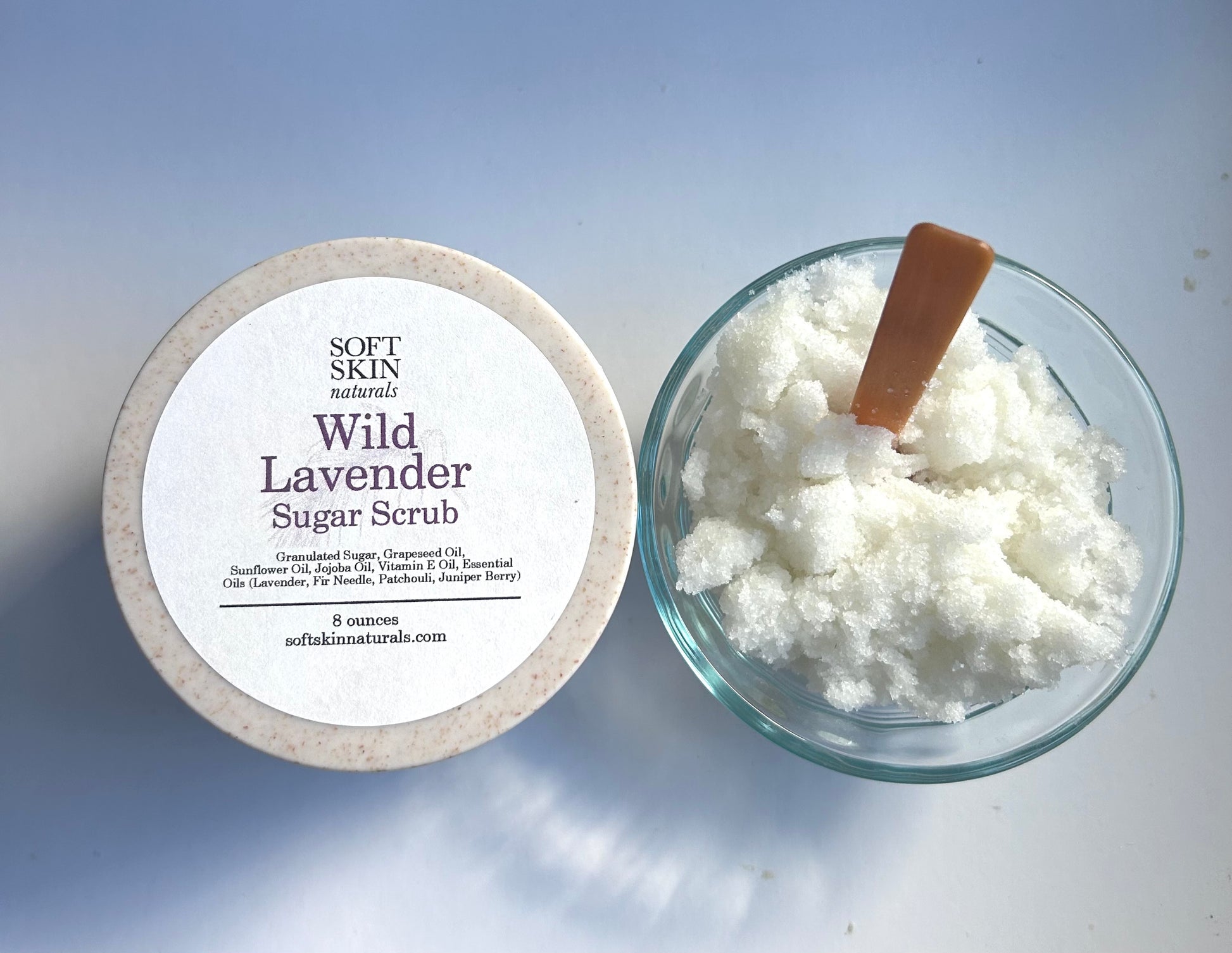 Wild Lavender Sugar Scrub with a container and wooden spoon on a light background