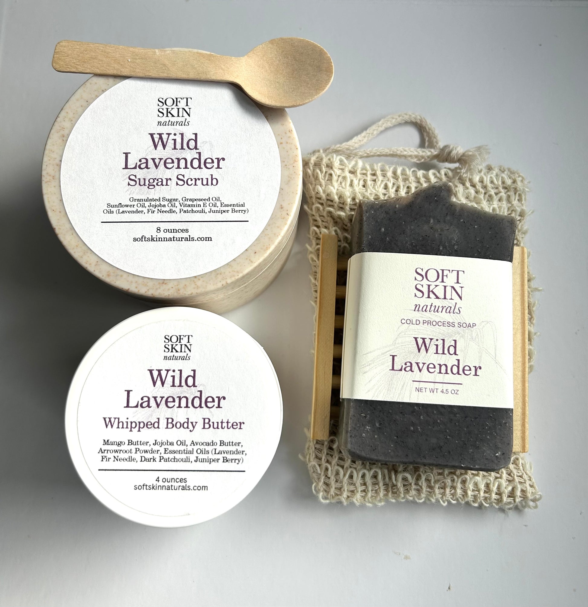 Wild Lavender skincare products including sugar scrub, soap, and body butter on a gray background.