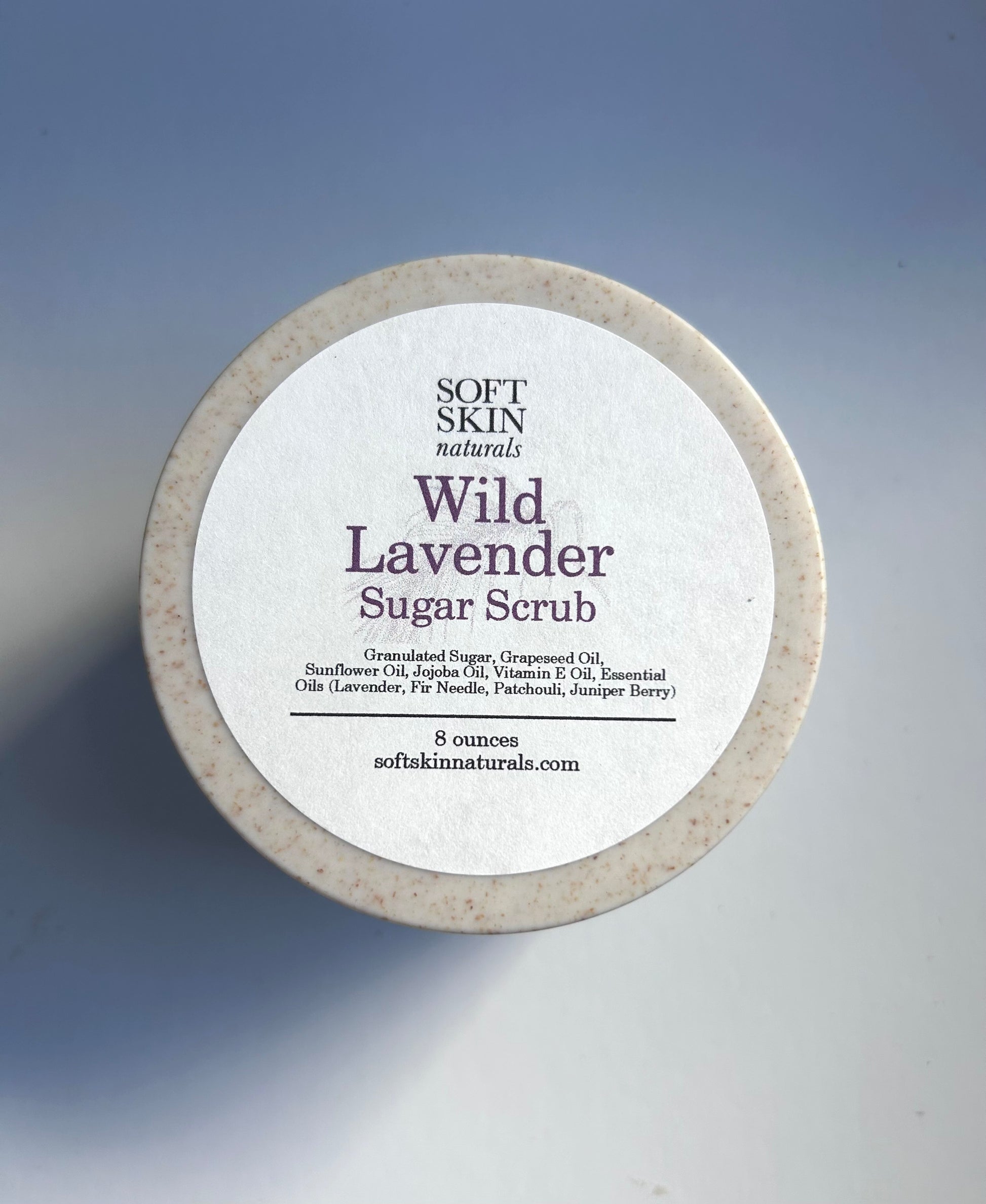 Wild Lavender Sugar Scrub container with label on a gradient blue background
