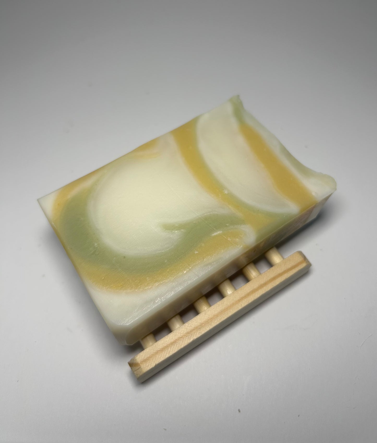 Bar of soap with a wooden soap dish on a gray background