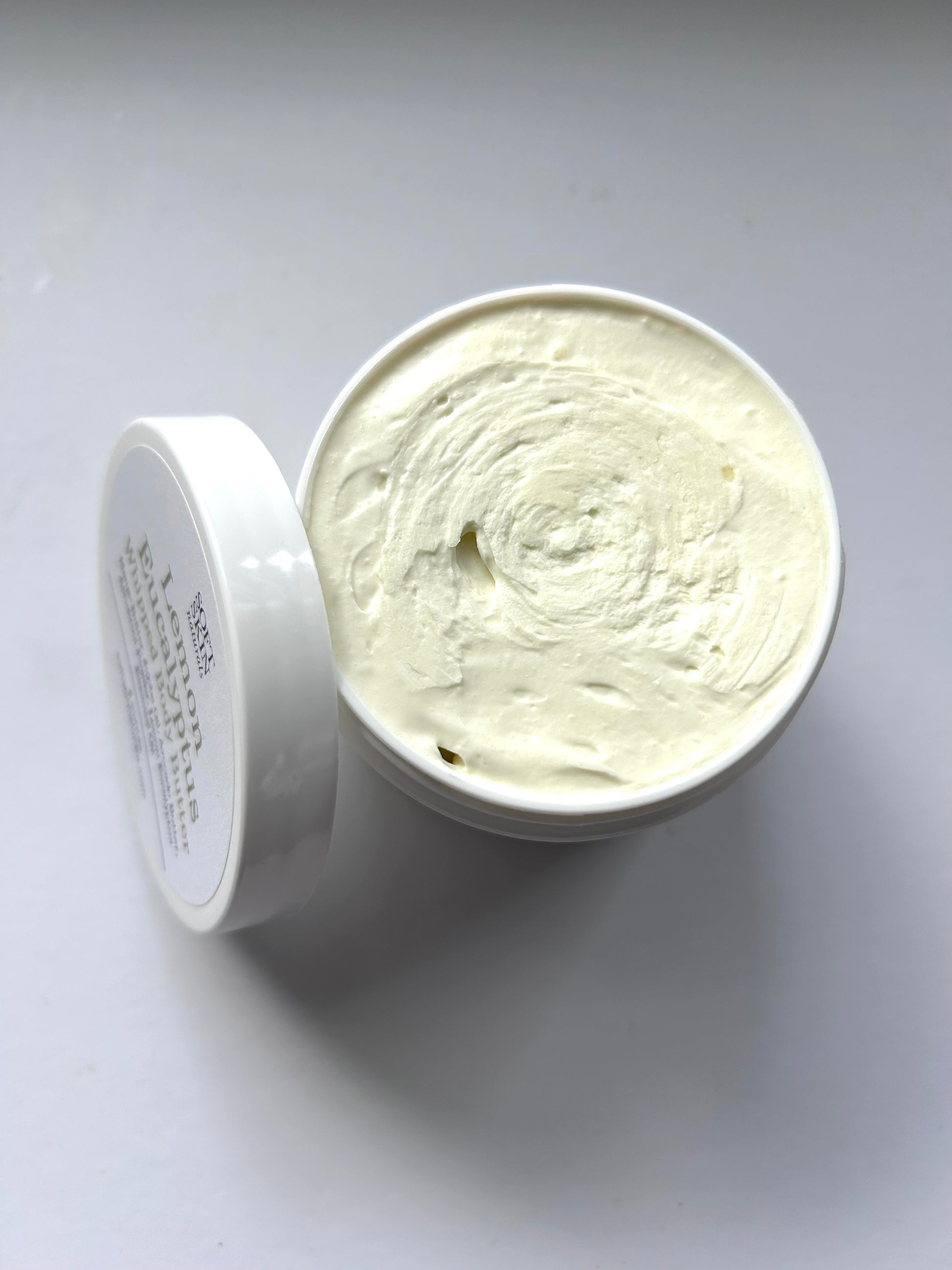White container of cream with a swirled texture on a white background
