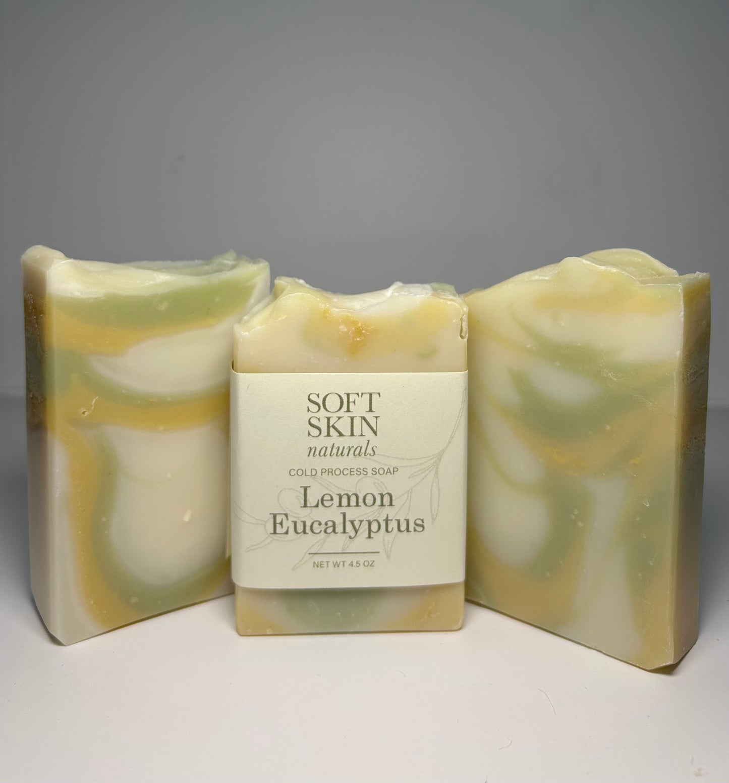 Three bars of soap with a central labeled bar on a gray background