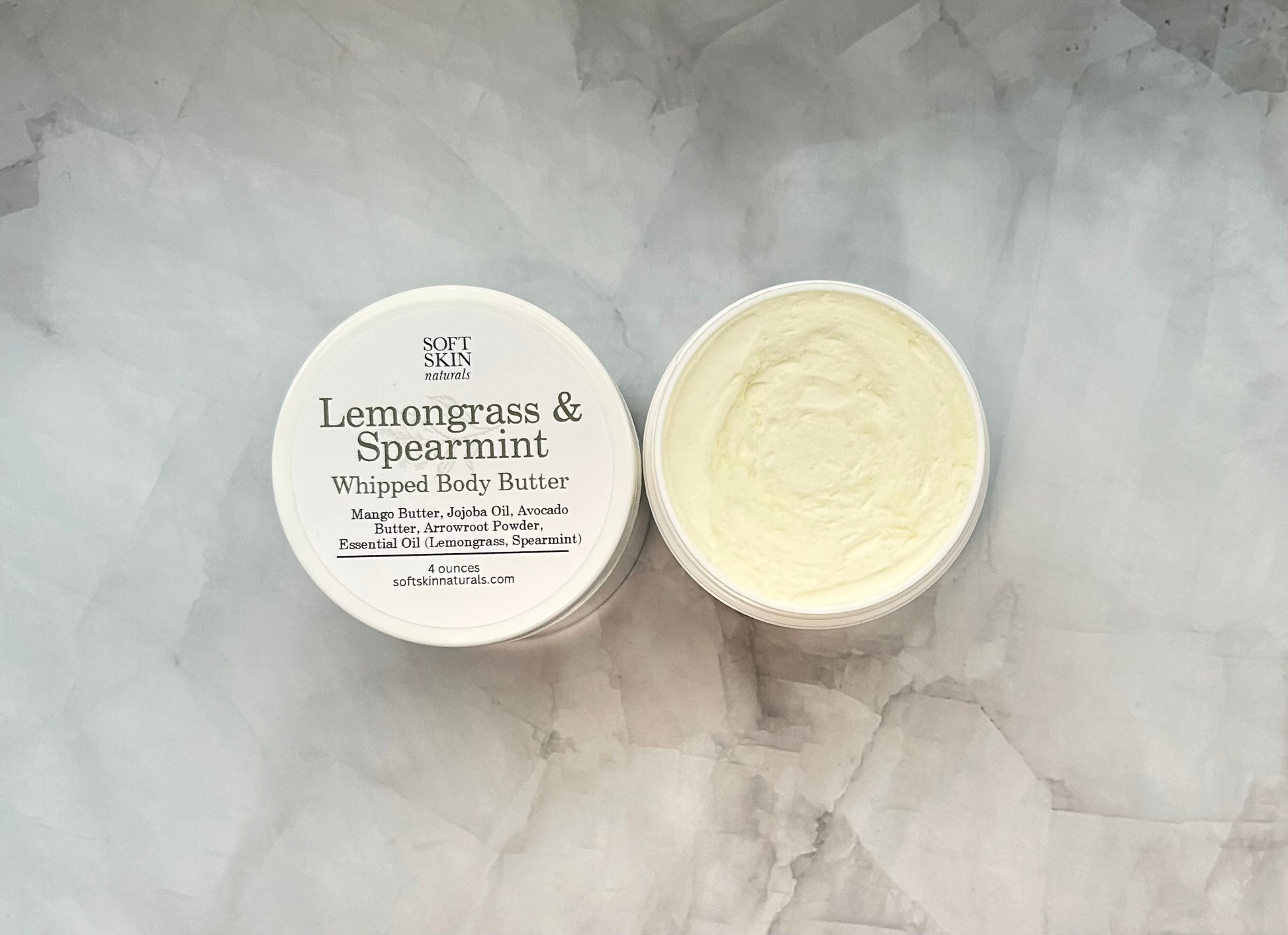 Whipped body butter container with lid on a textured gray background