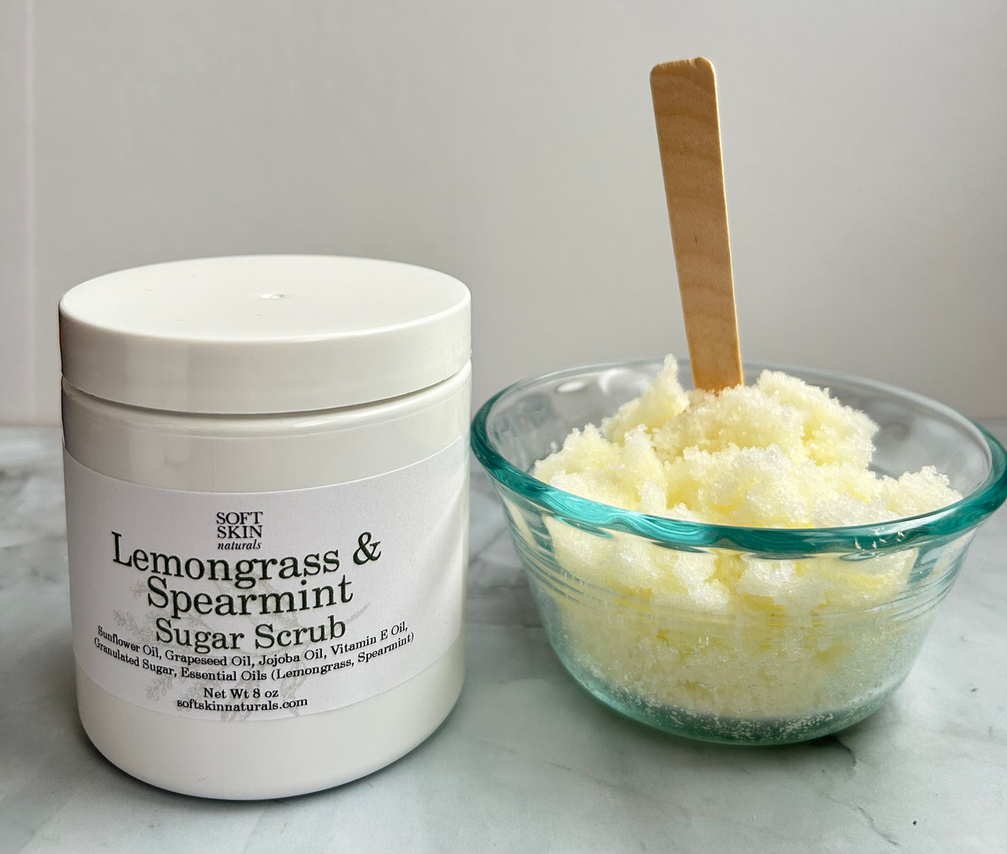 Jar of Lemongrass & Spearmint Sugar Scrub with a bowl of scrub next to it on a light background