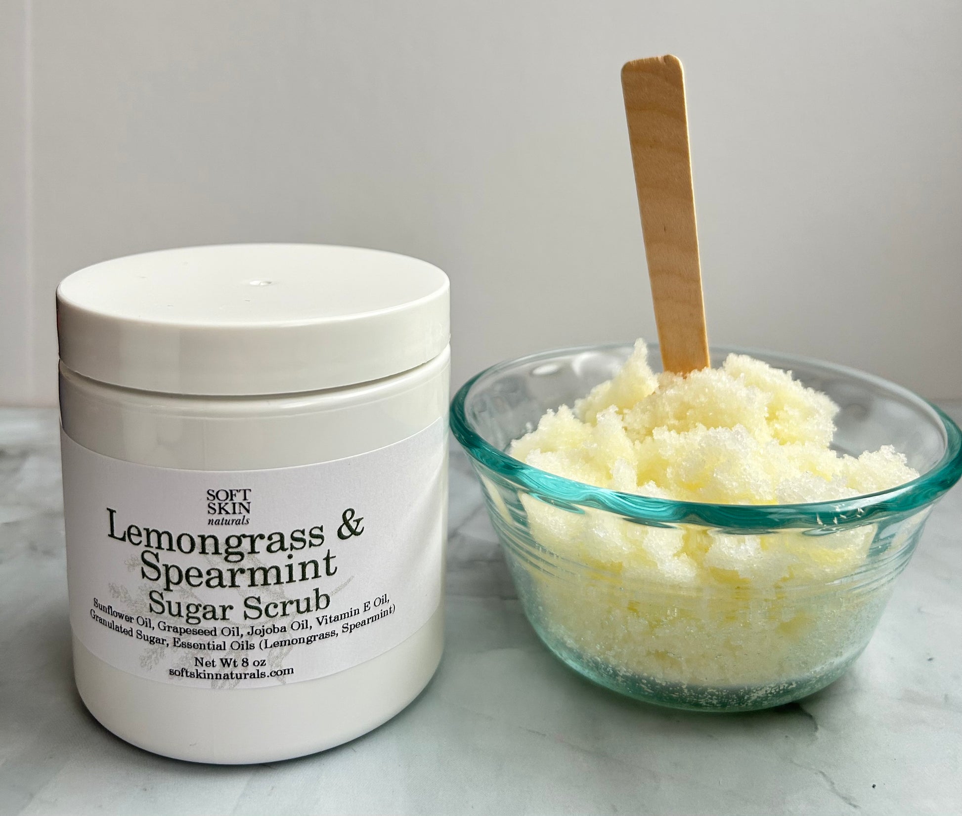 Jar of Lemongrass & Spearmint Sugar Scrub with a bowl of scrub next to it on a light background