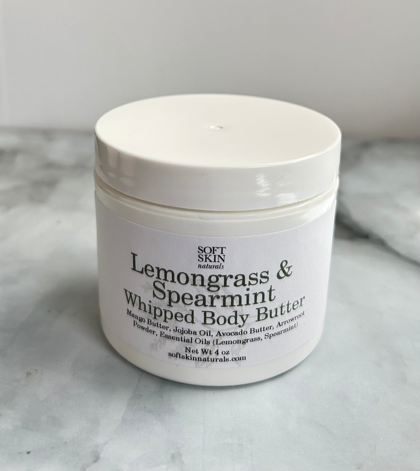 White jar of Lemongrass & Spearmint Whipped Body Butter on a marble surface