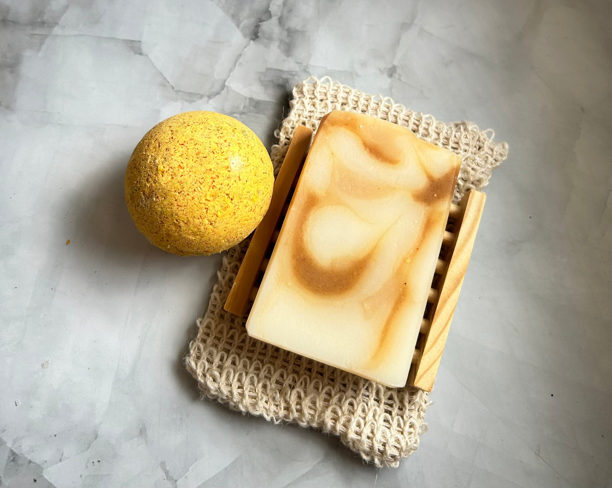 Bar of soap and yellow bath bomb on a textured surface