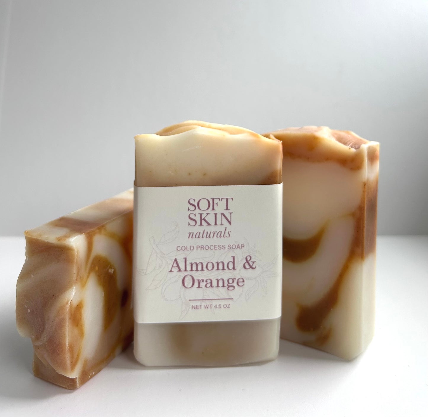 Two bars of almond and orange soap with a label on a white background