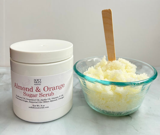 Almond & Orange Sugar Scrub container with a glass bowl of scrub on a white surface