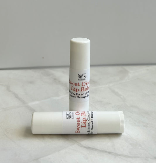 Two lip balms with Sweet Orange flavor on a light gray surface