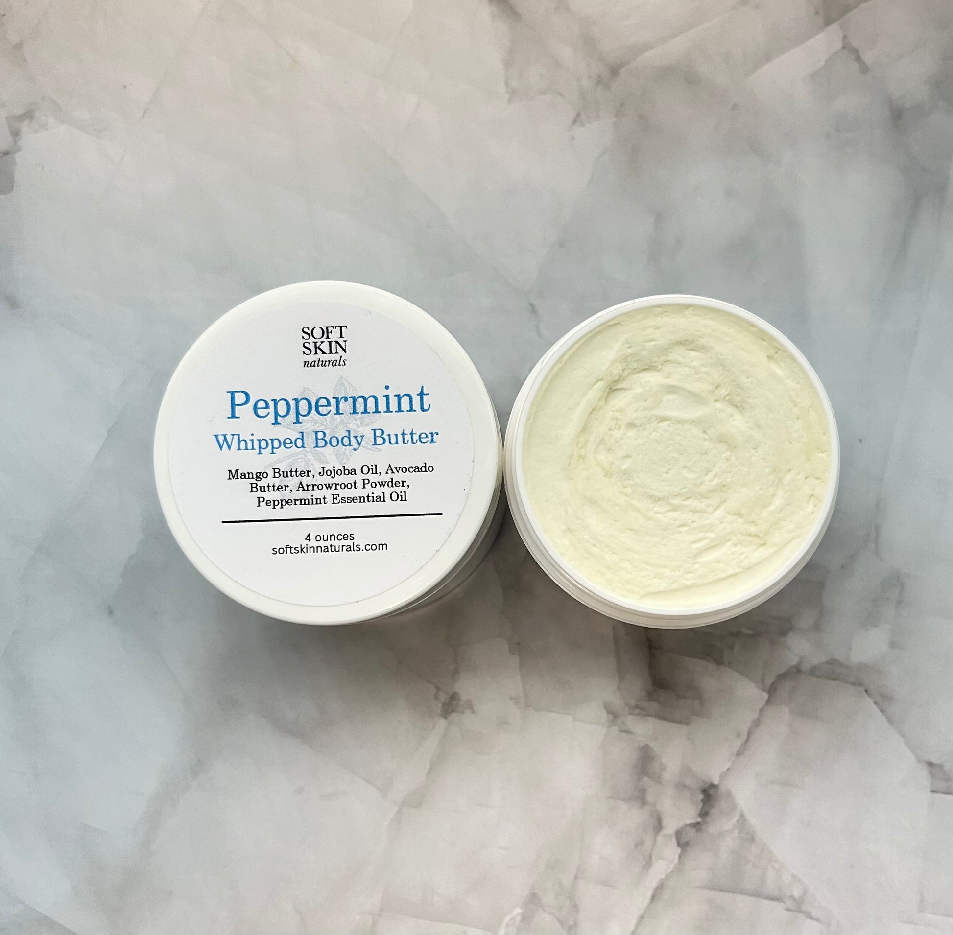 Peppermint whipped body butter with a visible label on a marble surface