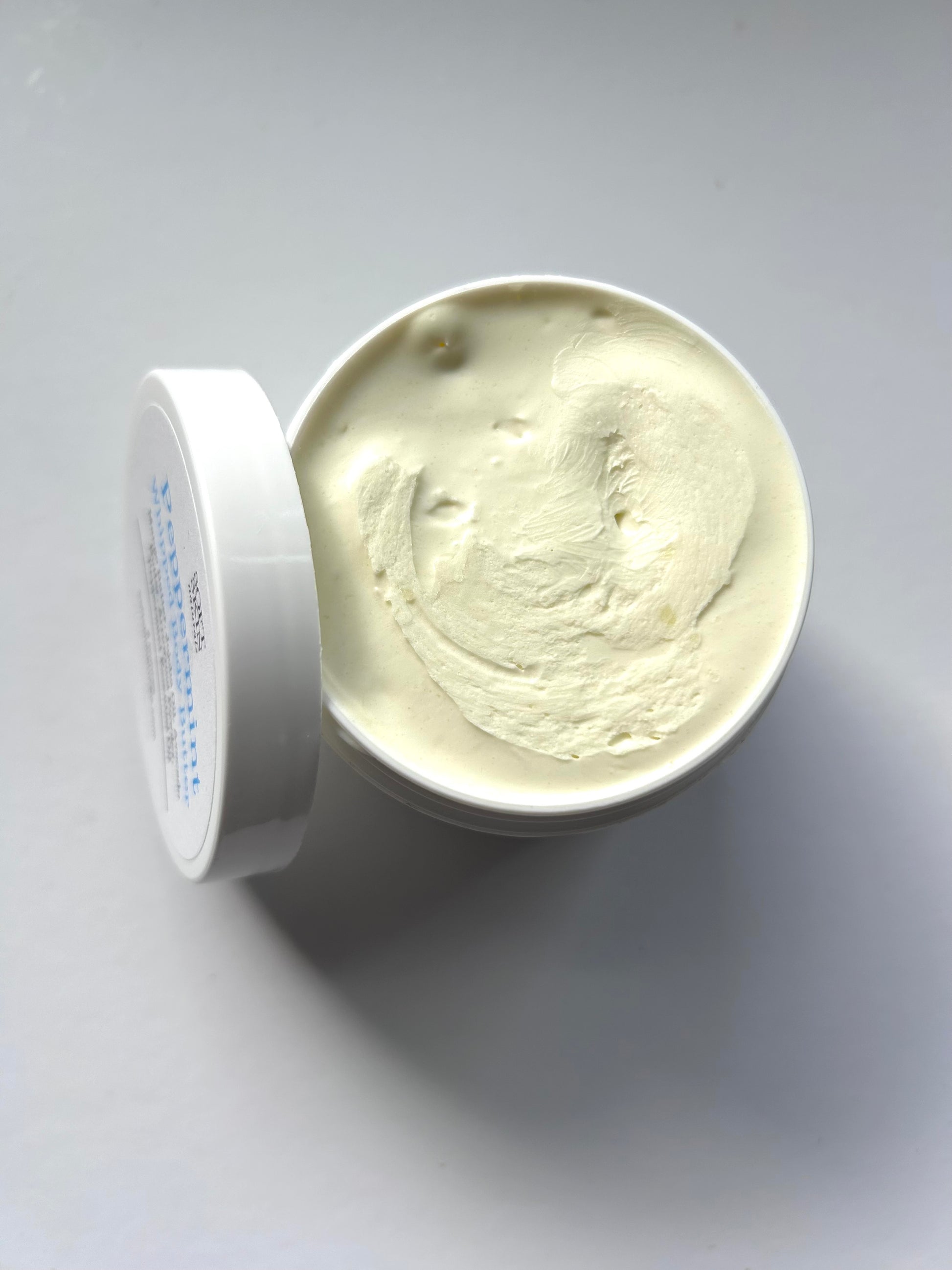 Open container of cream on a gray background