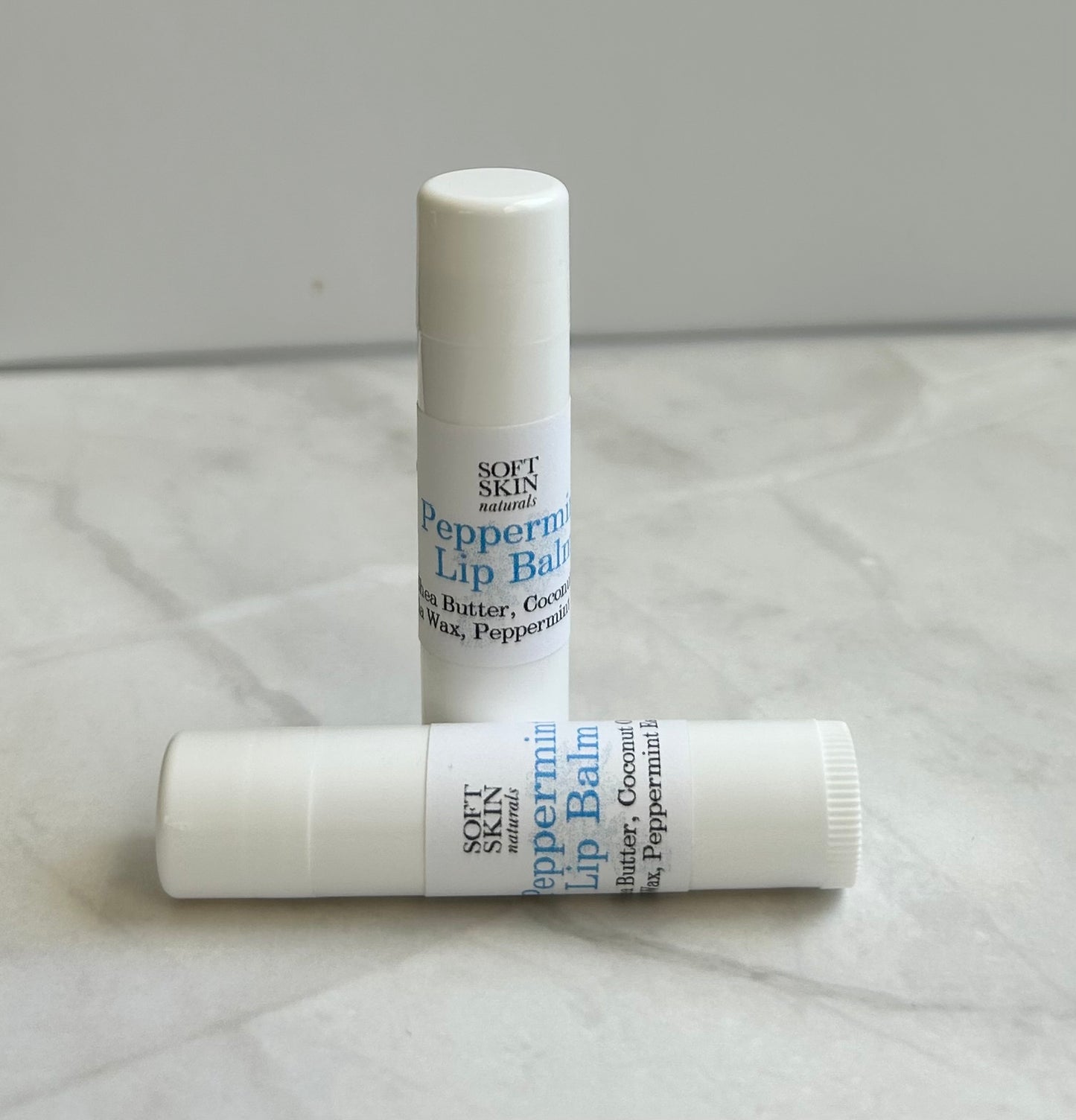 Two lip balms with 'Soft Skin' branding on a light gray background