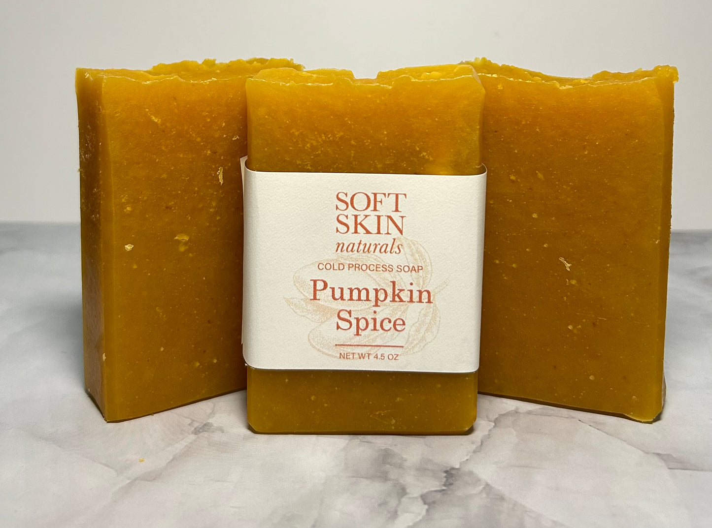 Three bars of pumpkin spice soap with a visible label on a marble surface.