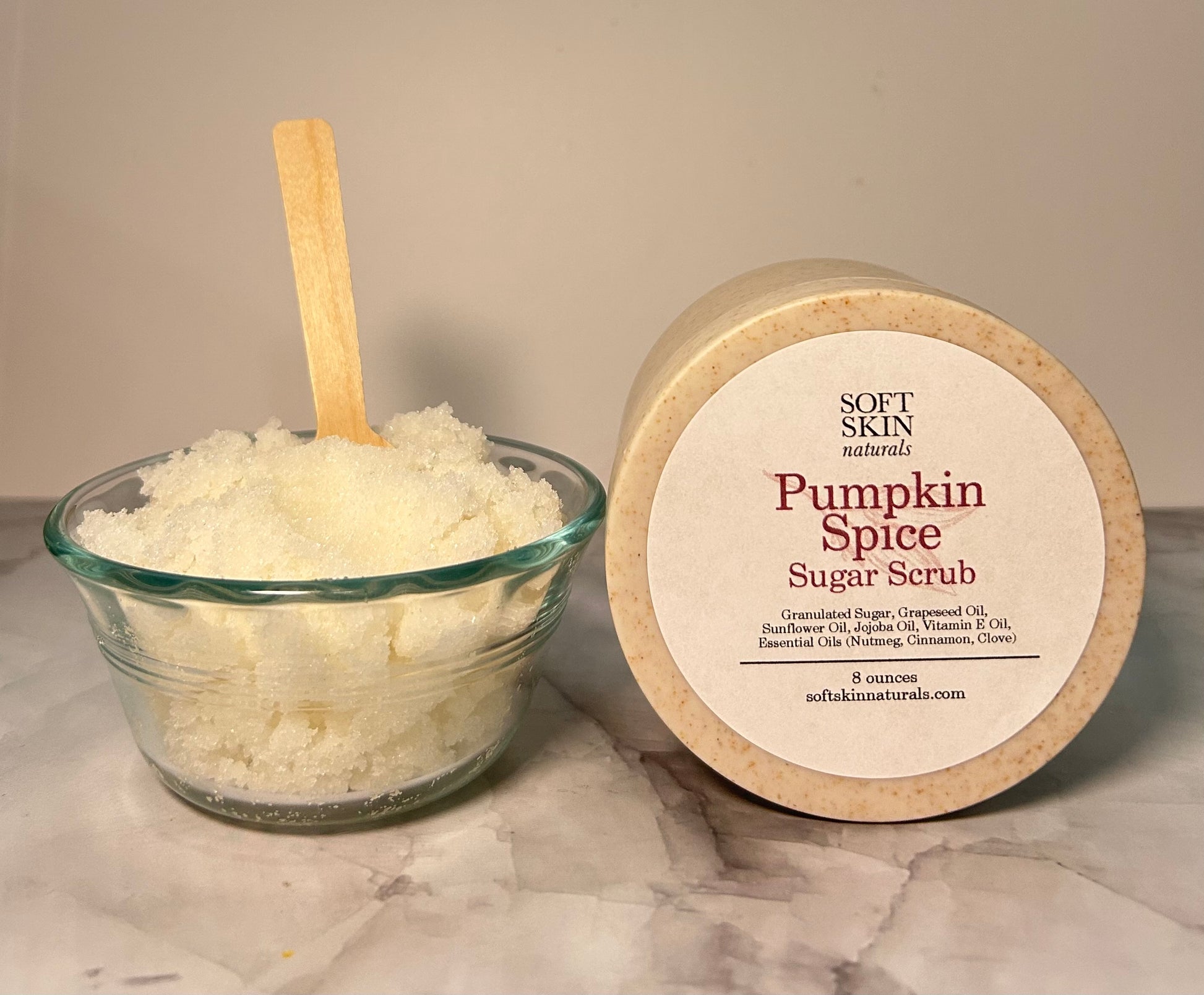 Pumpkin Spice Sugar Scrub with a wooden spoon and container on a marble surface
