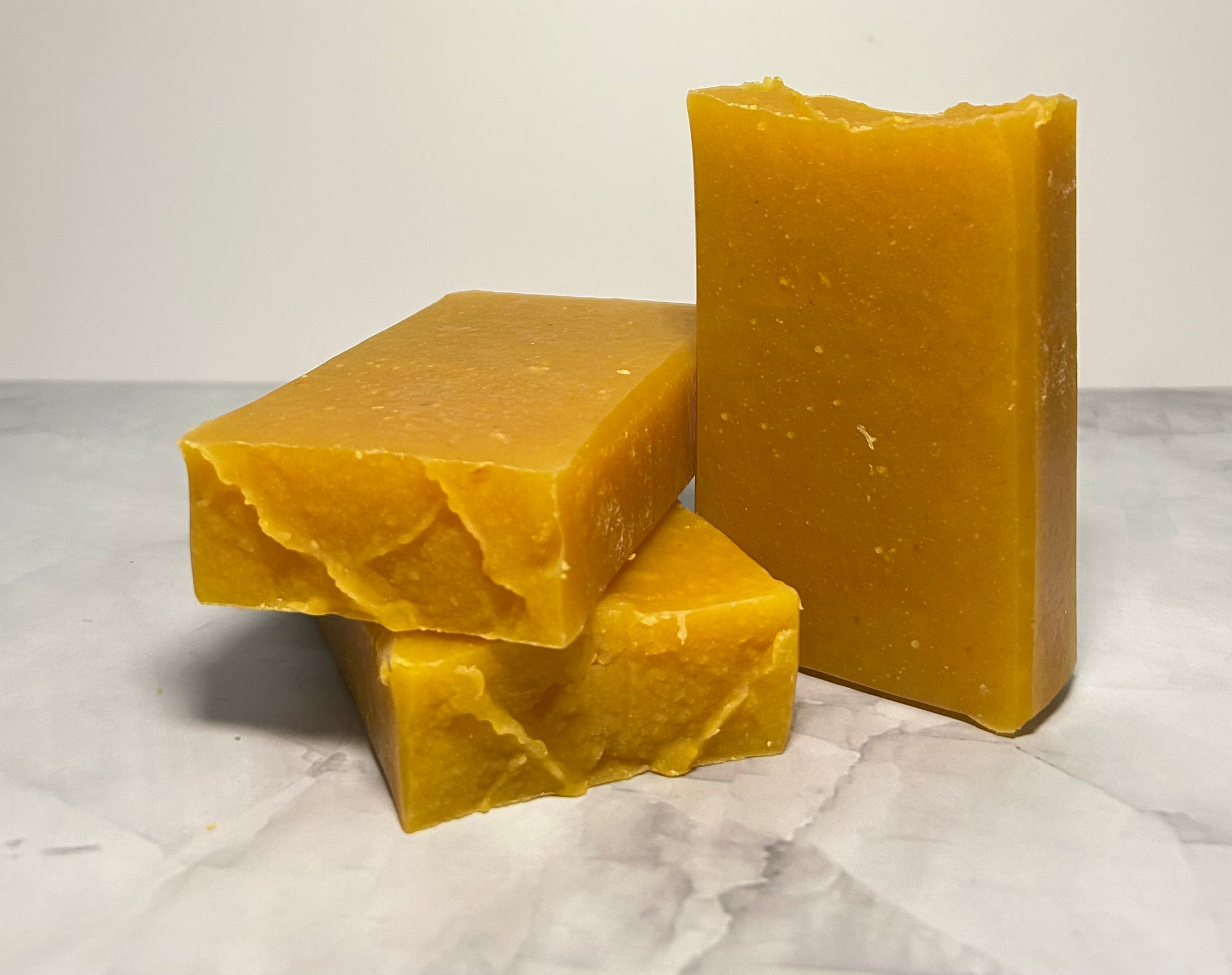 Three bars of yellow soap on a marble surface with a white background