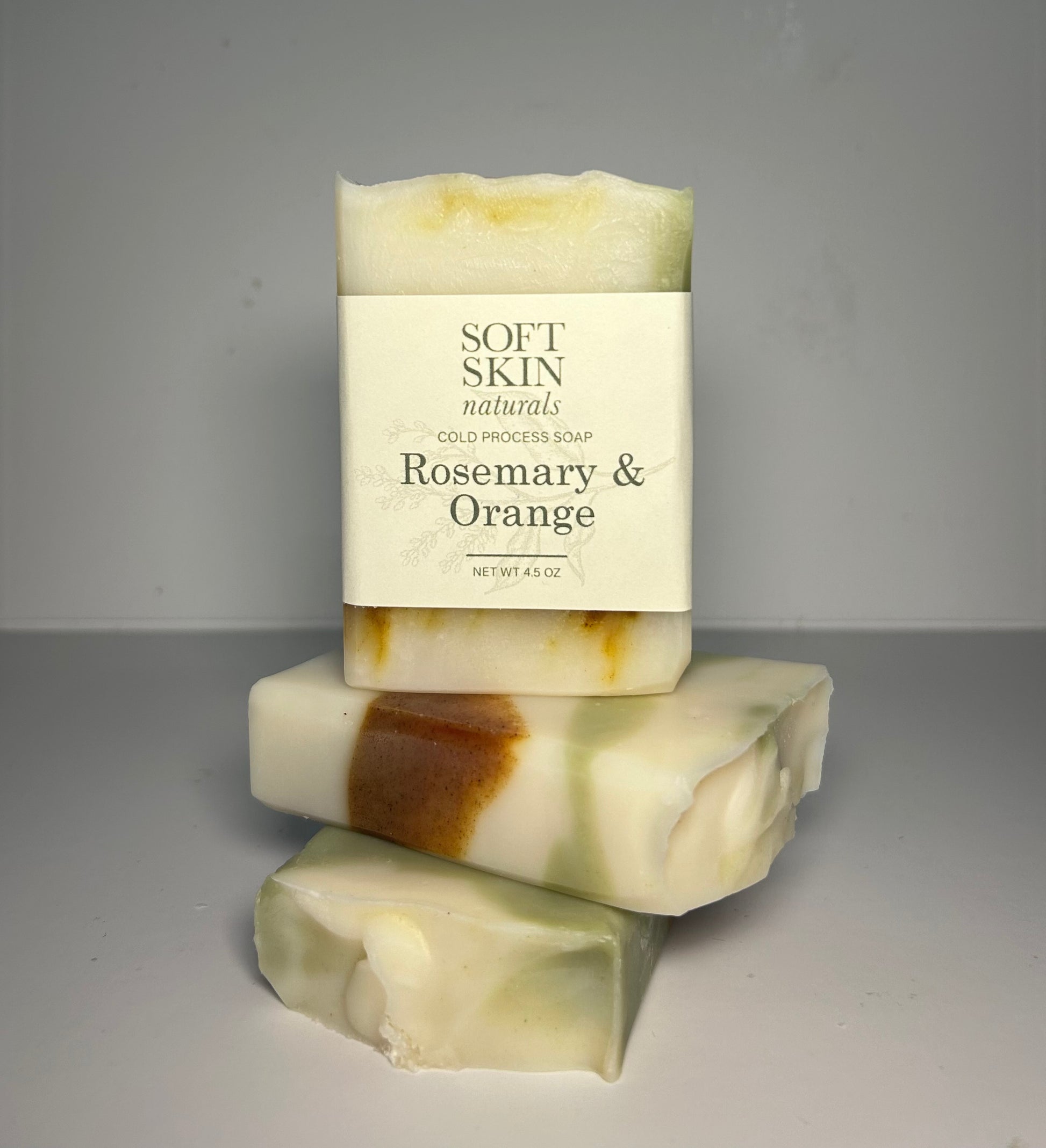 Stack of three bars of soap with a Soft Skin Naturals label on a gray background