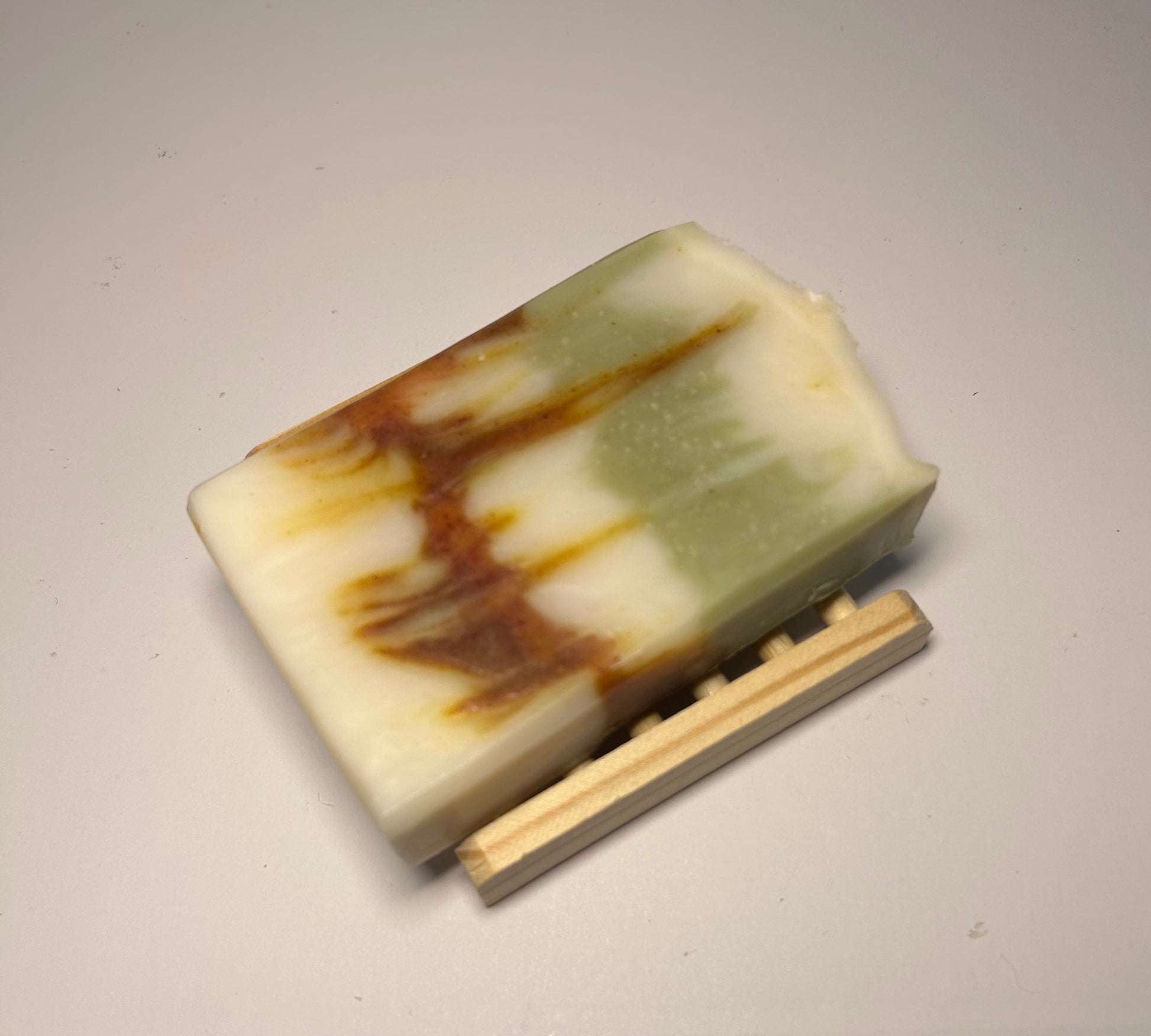 Marbled soap bar with a wooden soap dish on a light gray background