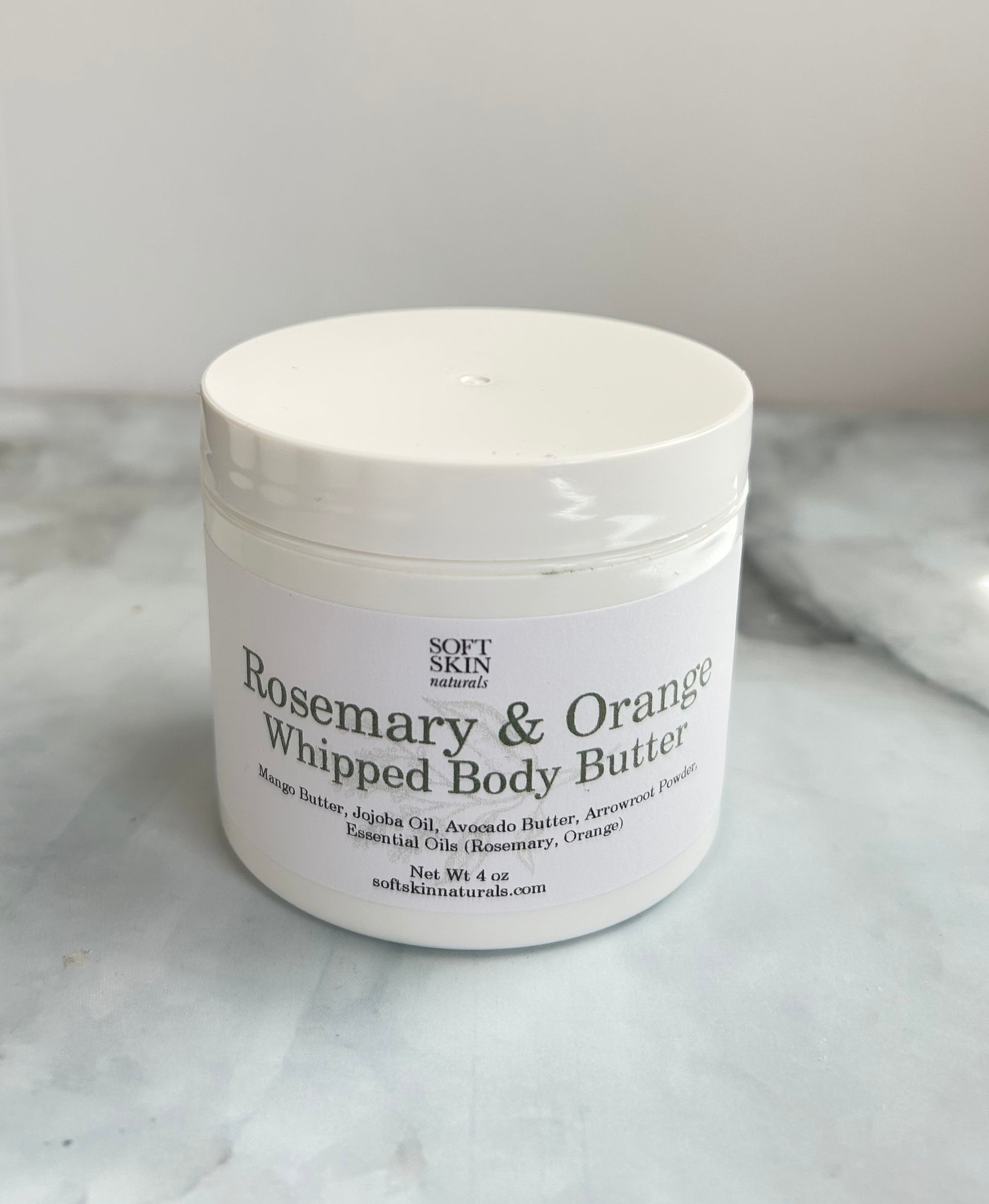 White jar of Rosemary & Orange Whipped Body Butter on a marble surface