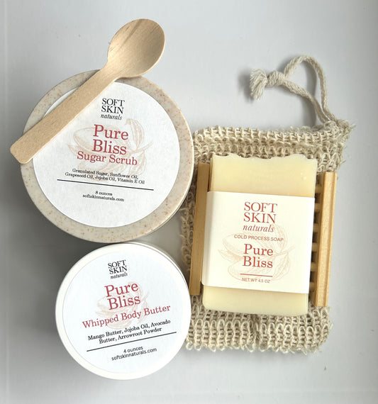 Soft Skin Naturals Pure Bliss product set including sugar scrub, body butter, and soap on a light gray background.