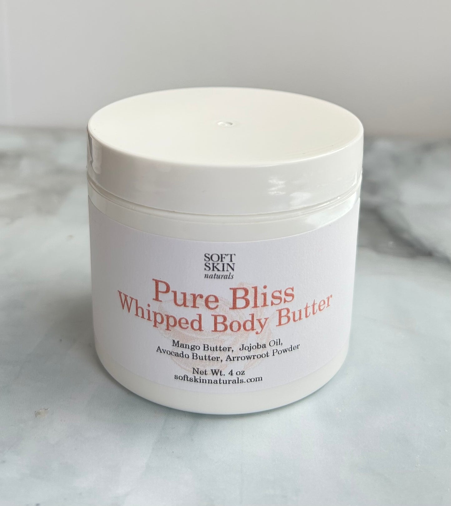 White jar of Pure Bliss Whipped Body Butter on a marble surface