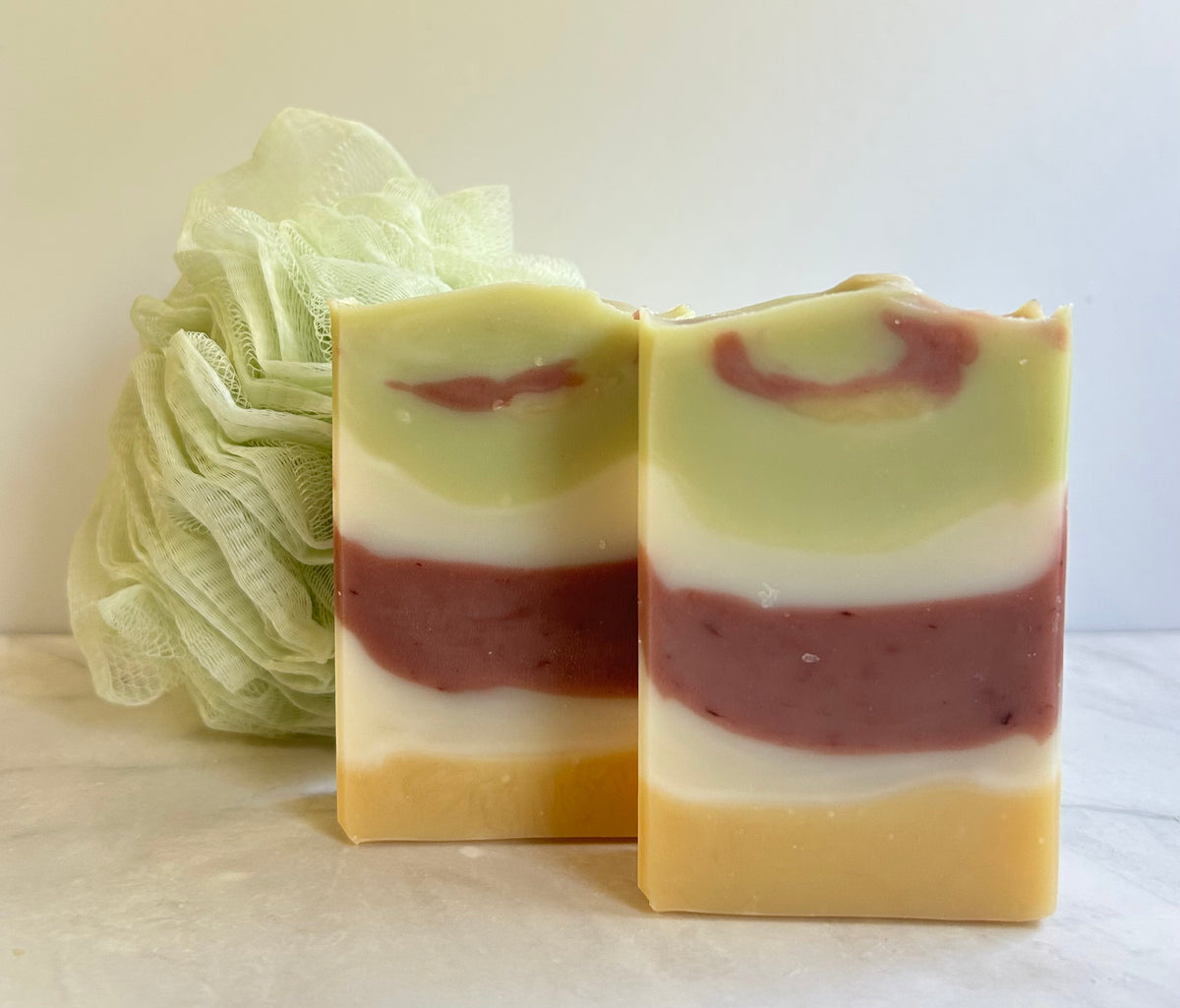 Two bars of soap that are colored red, white, green, and yellow.
