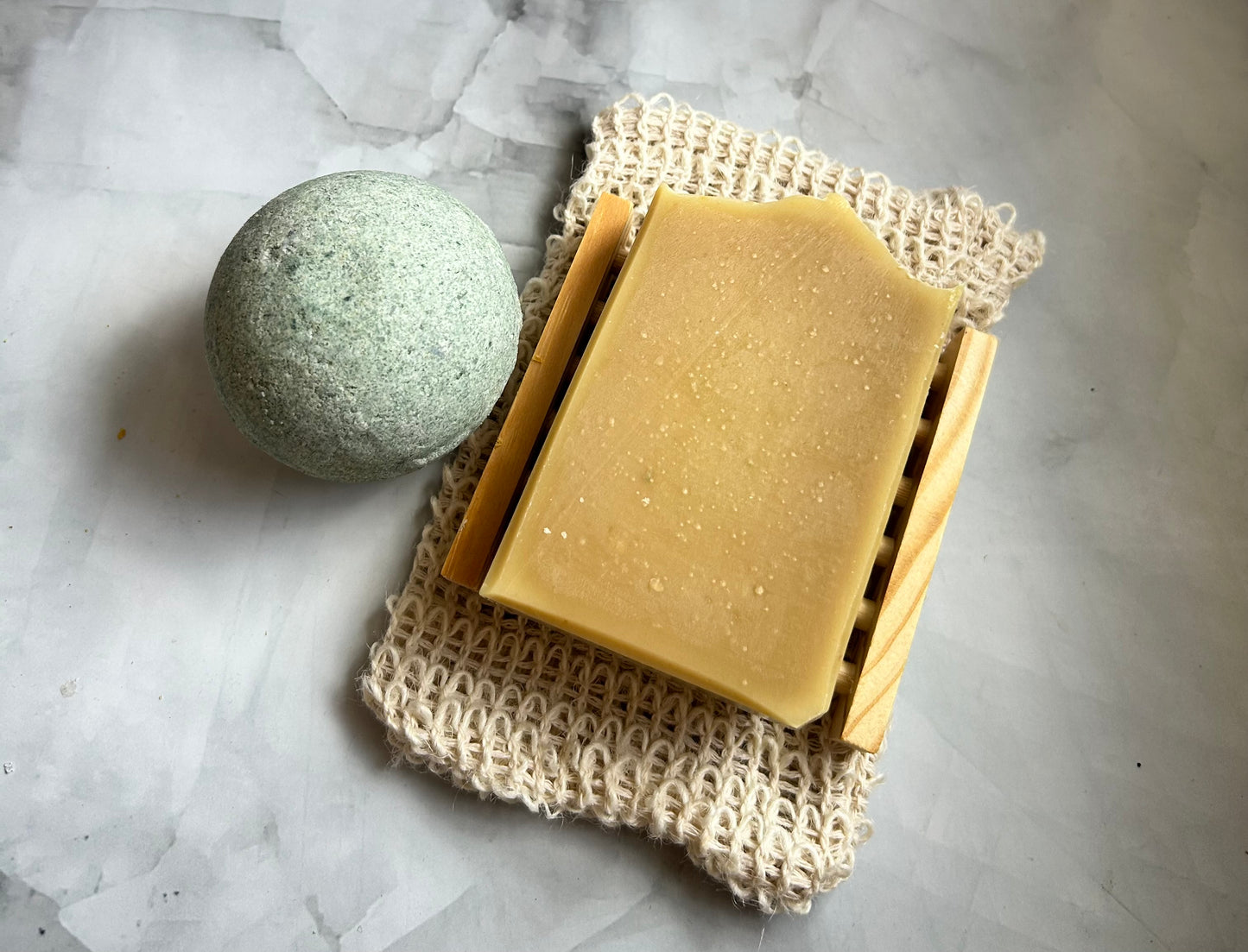 Bar of soap and a bath bomb, on a textured white surface.
