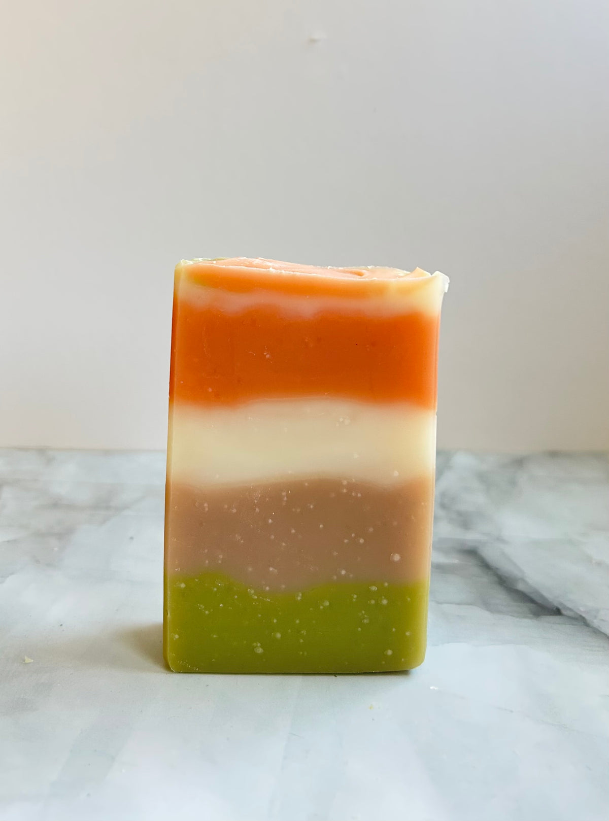 Multicolored striped soap bar on a white surface with a light gray background